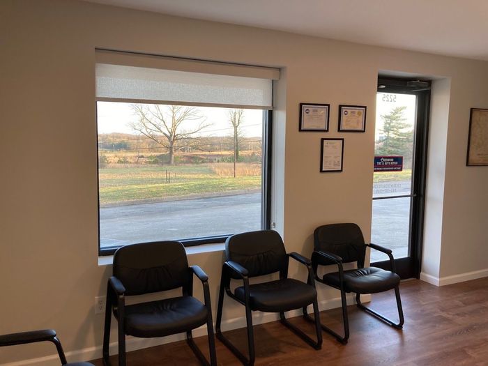 a waiting room with three chairs and a window .