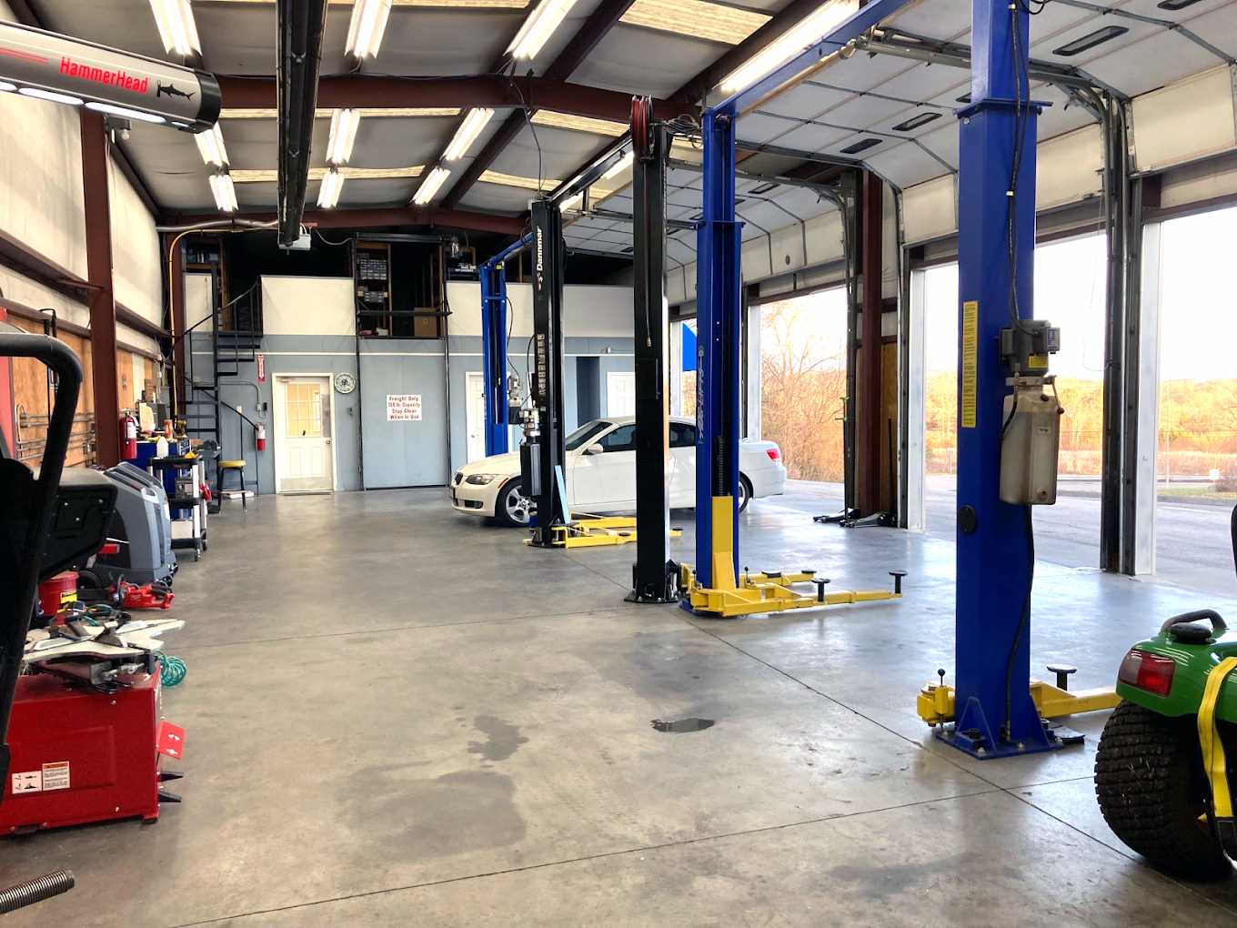a tractor is parked in a garage with cars on lifts .