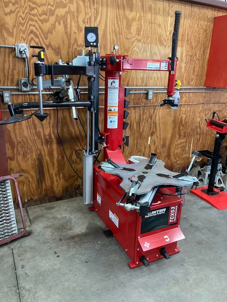 a tire changer is sitting in a garage next to a wooden wall .