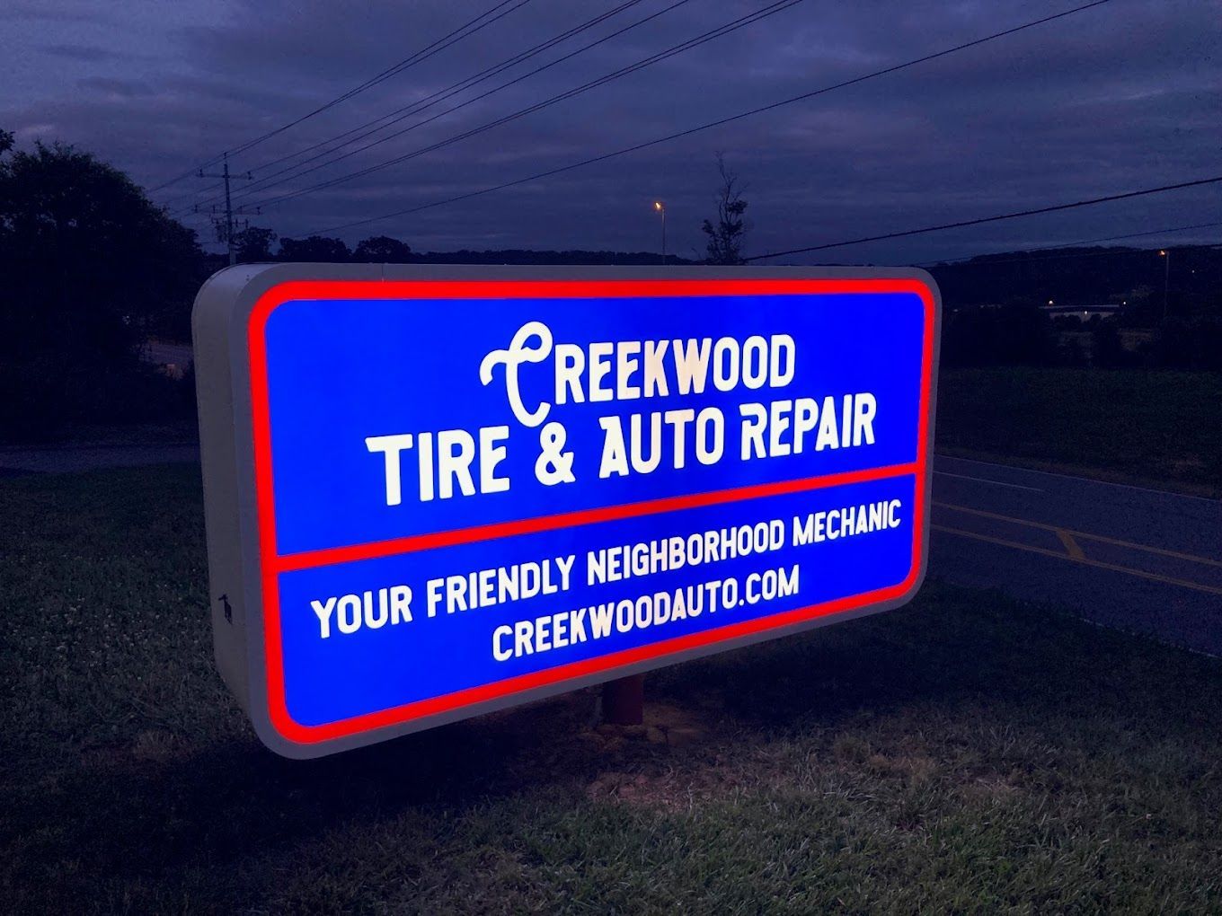 a blue sign for creekwood tire and auto repair