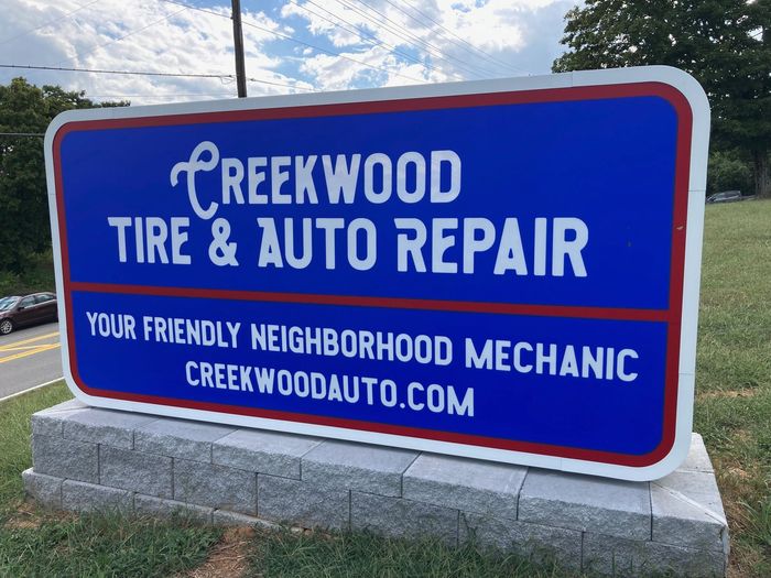 a blue sign for creekwood tire and auto repair