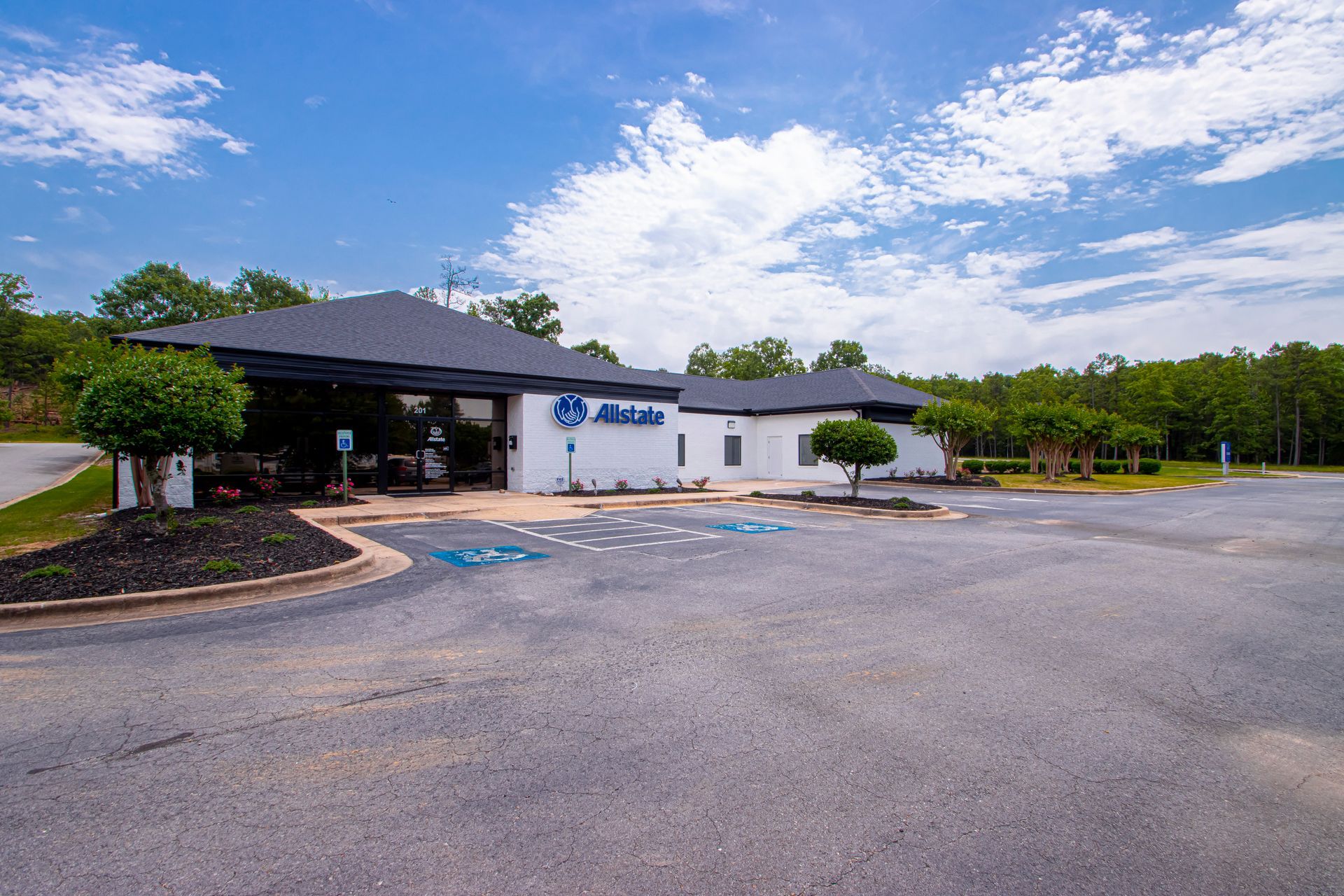 Single-story building with a dark roof and white exterior in a parking lot with accessible spaces under a blue sky.