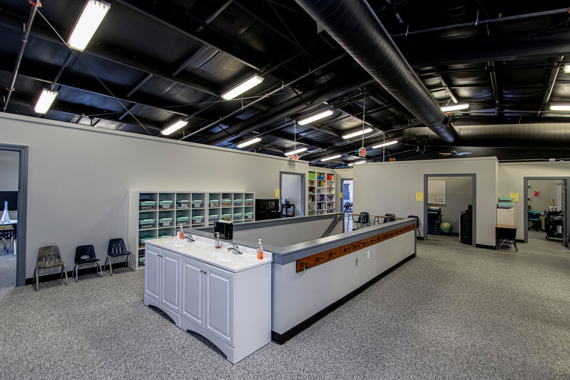 Modern interior of a medical or clinical reception area featuring a central white desk, shelving, and doorways.