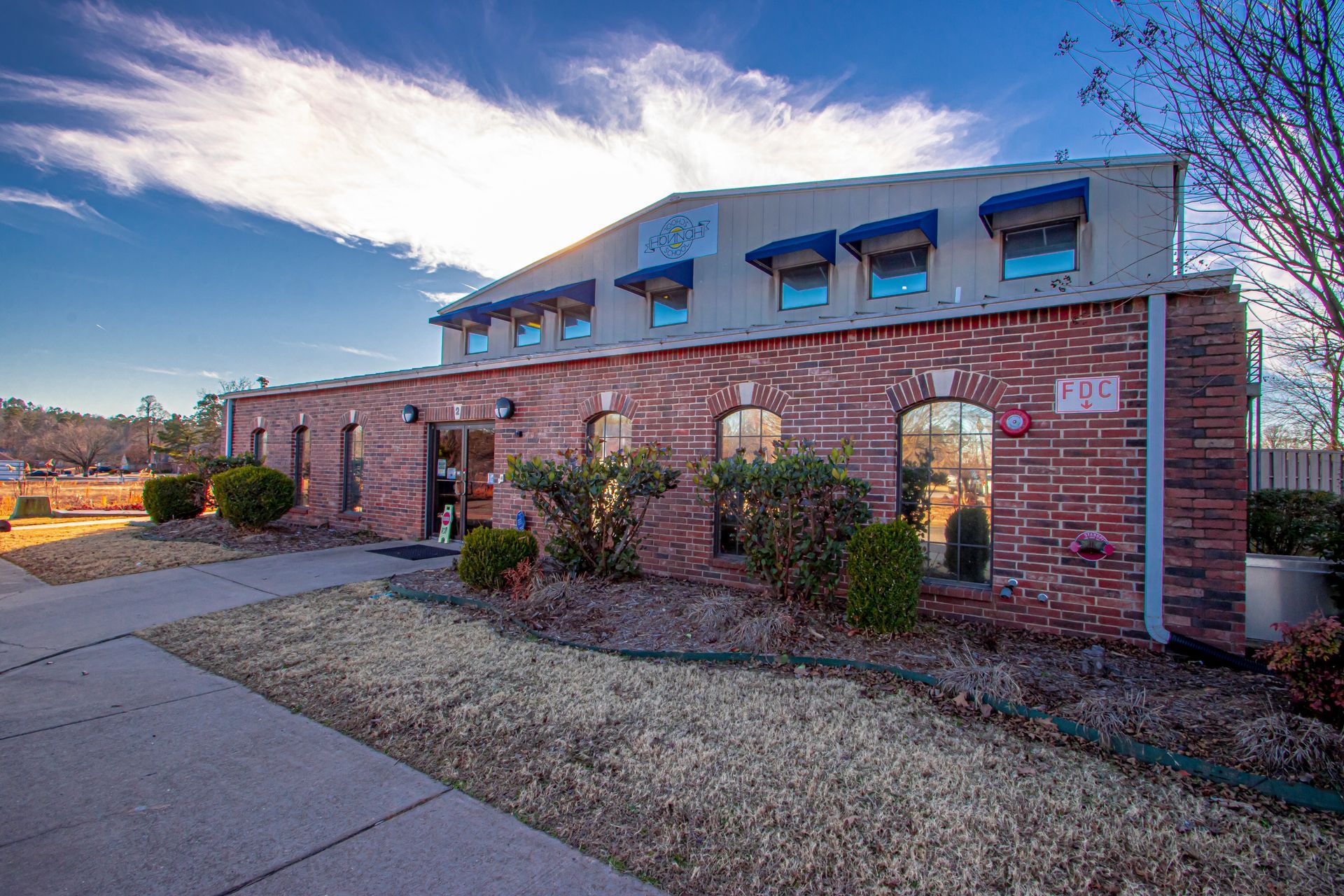 Low-angle shot of a brick office building with a concrete sidewalk under a bright, sunny sky.