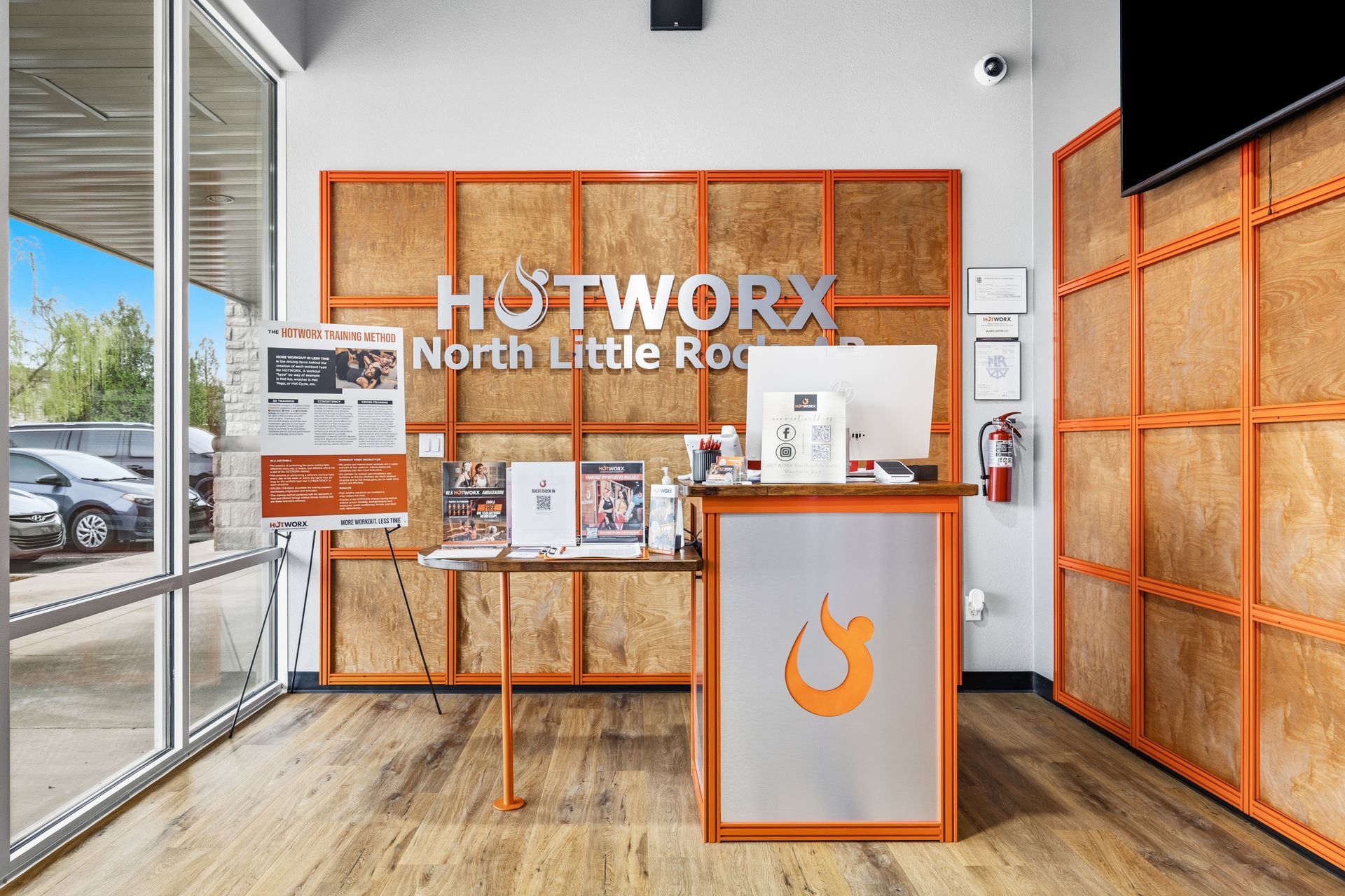 The front desk of a HOTWORX studio in North Little Rock featuring an orange wood-paneled wall, flooring, and branded counter.