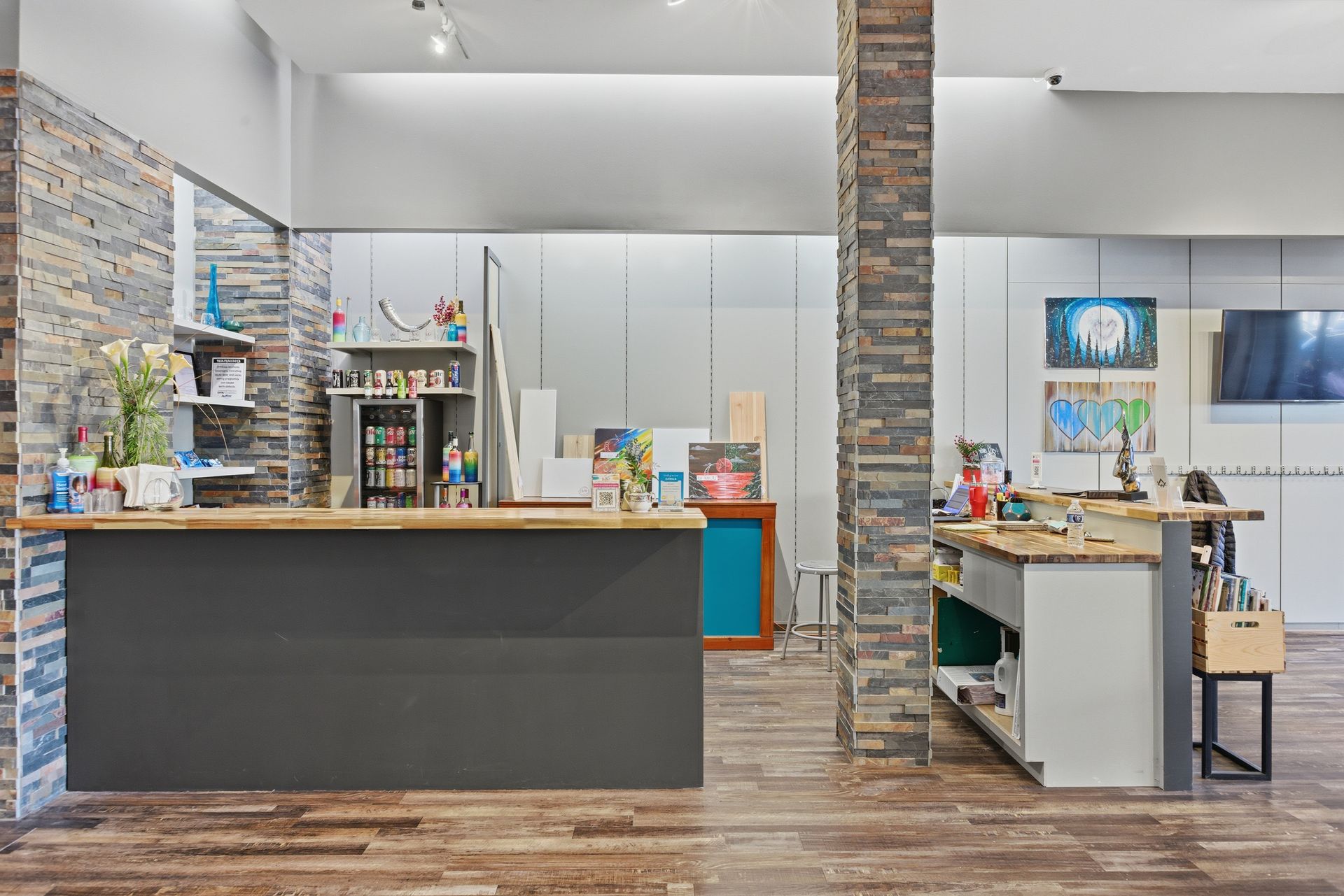 A reception area featuring a dark gray service desk, stone-accented columns, and wooden flooring in a modern office space.