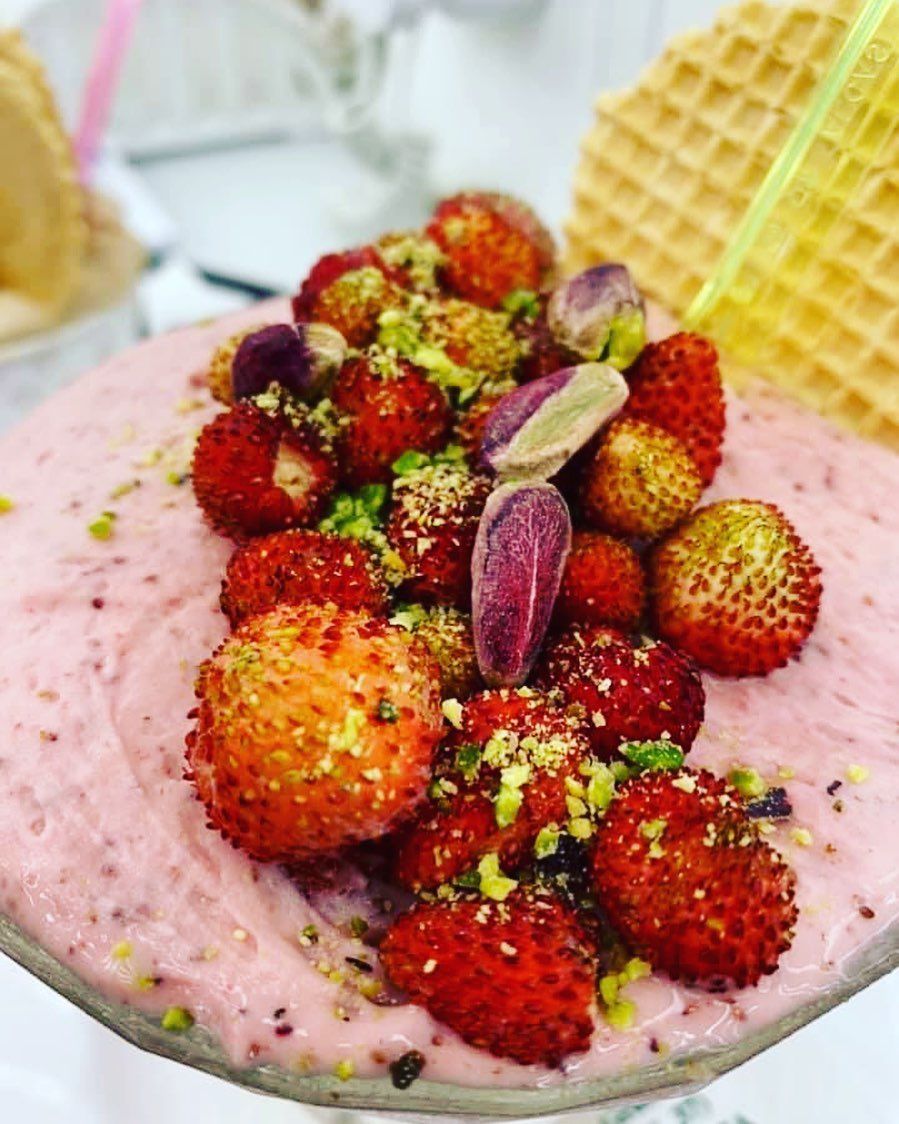 Dessert rosa con fragole, pistacchi e guarnizione di waffle.