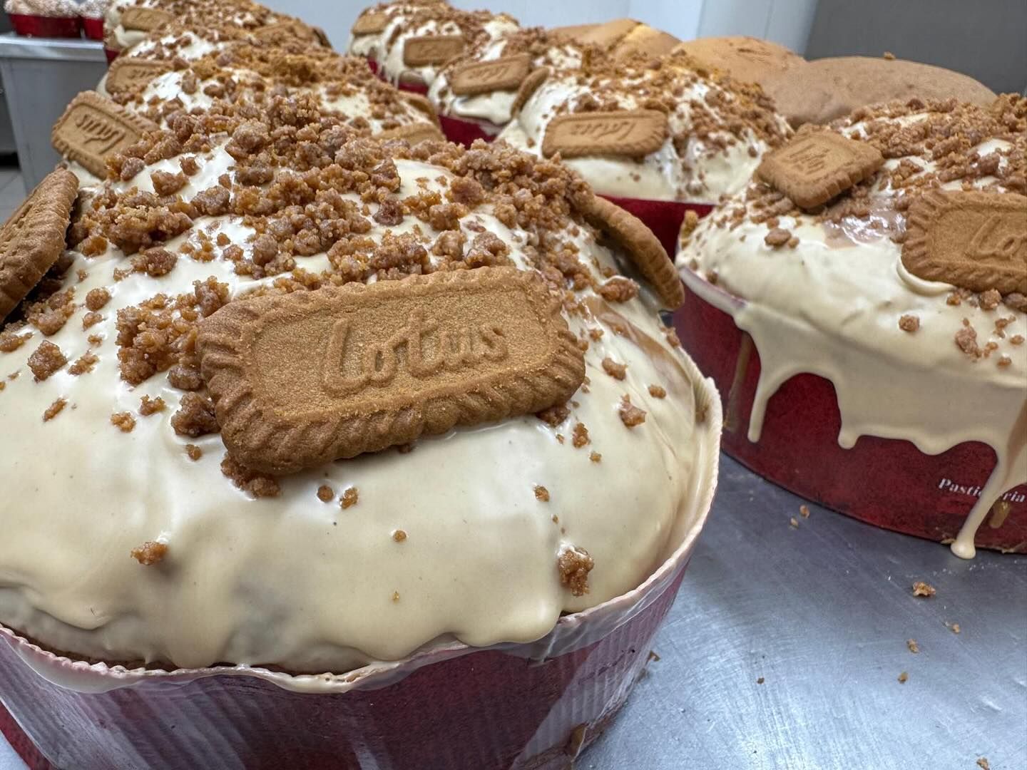 Torte con glassa Biscoff in pirottini di carta rossi, ricoperte di glassa bianca e con briciole di Biscoff e biscotti sopra.