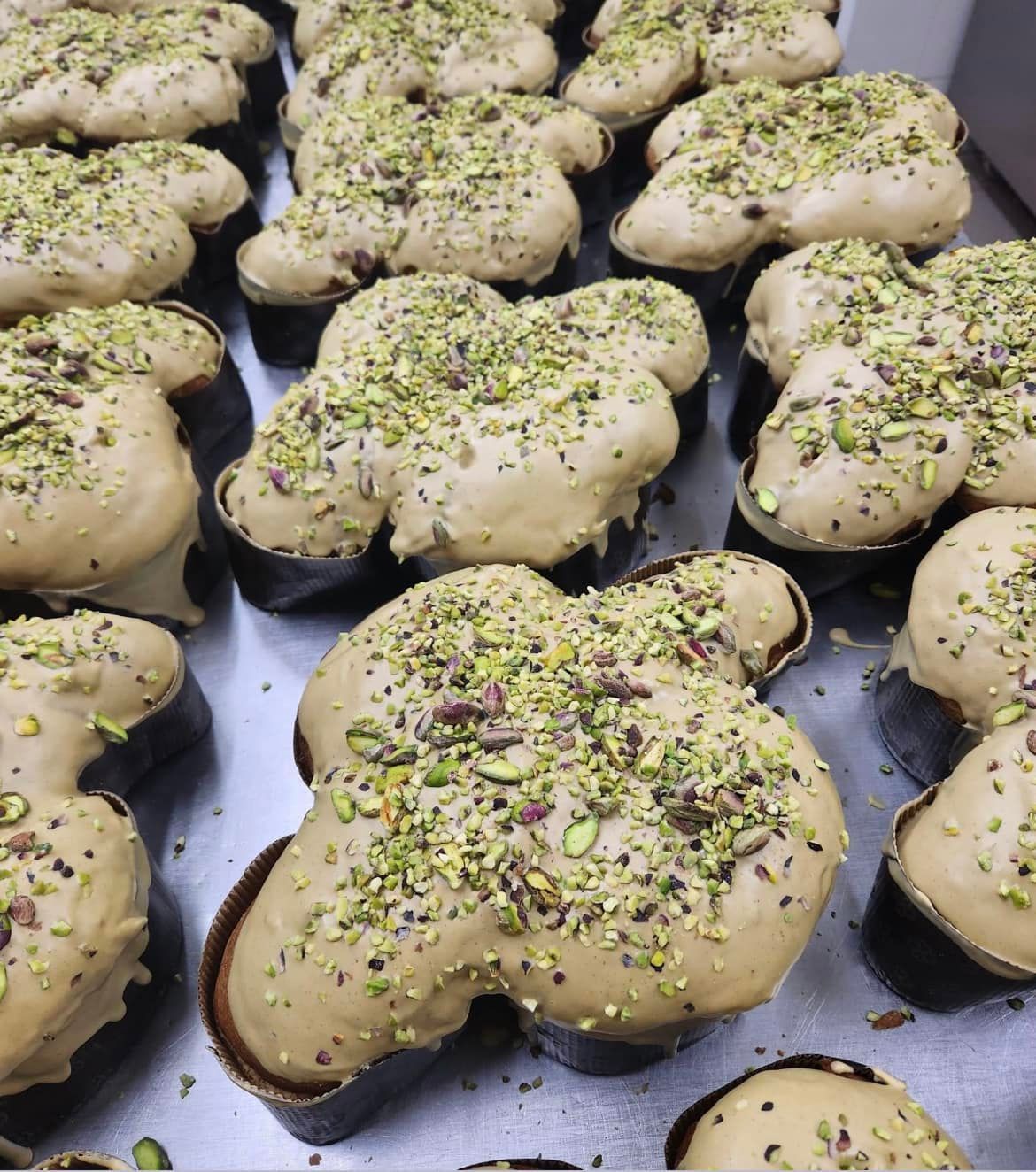File di colombe a forma di colomba, spolverate di pistacchi, su un vassoio di metallo.