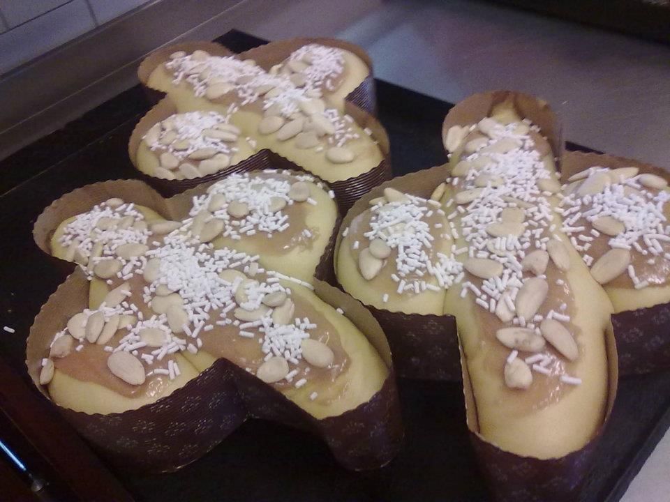 Dolci pasquali a forma di croce con copertura di mandorle, esposti su una teglia da forno.