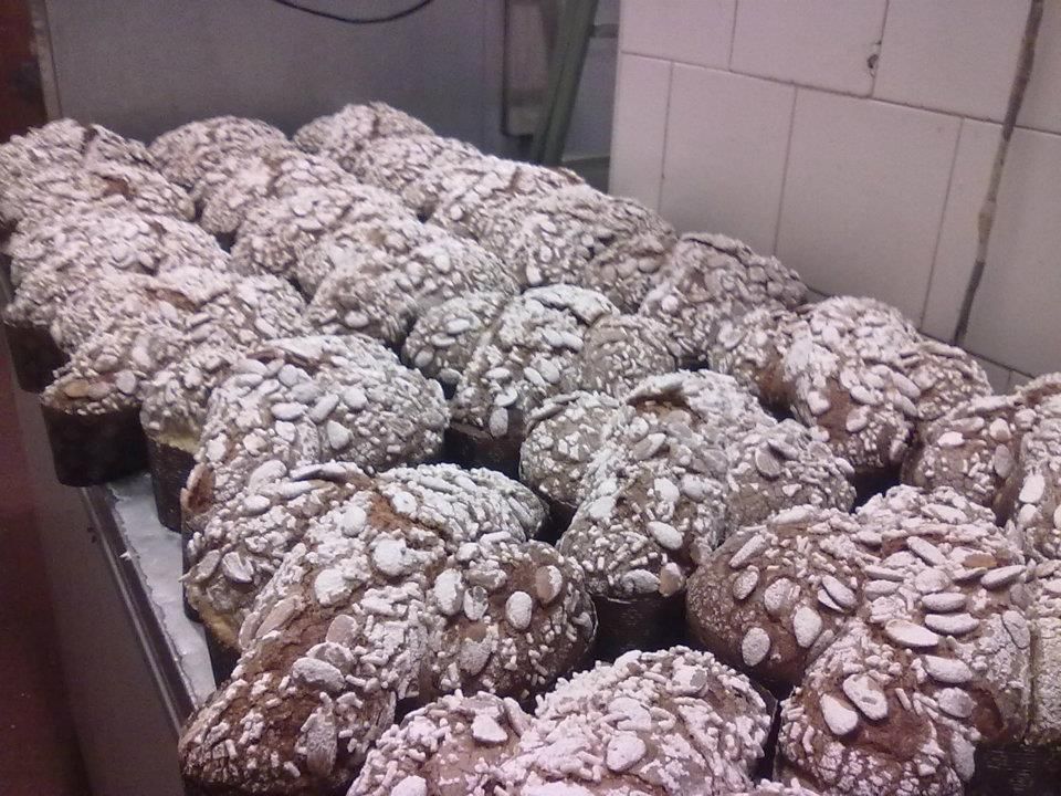 File di prodotti da forno rotondi e semini su una superficie metallica, probabilmente in una panetteria.