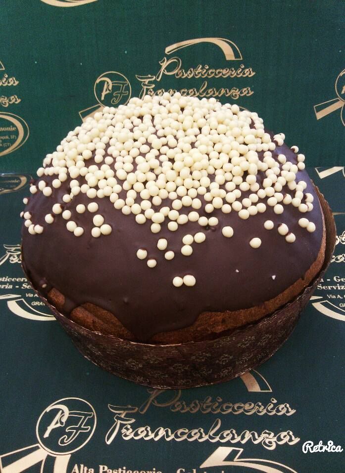 Torta rotonda al cioccolato con granella bianca su sfondo verde.