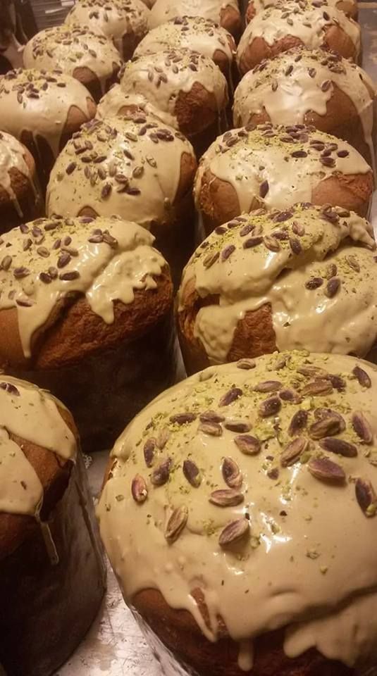 File di pasticcini a cupola con glassa chiara e spolverati di pistacchi.