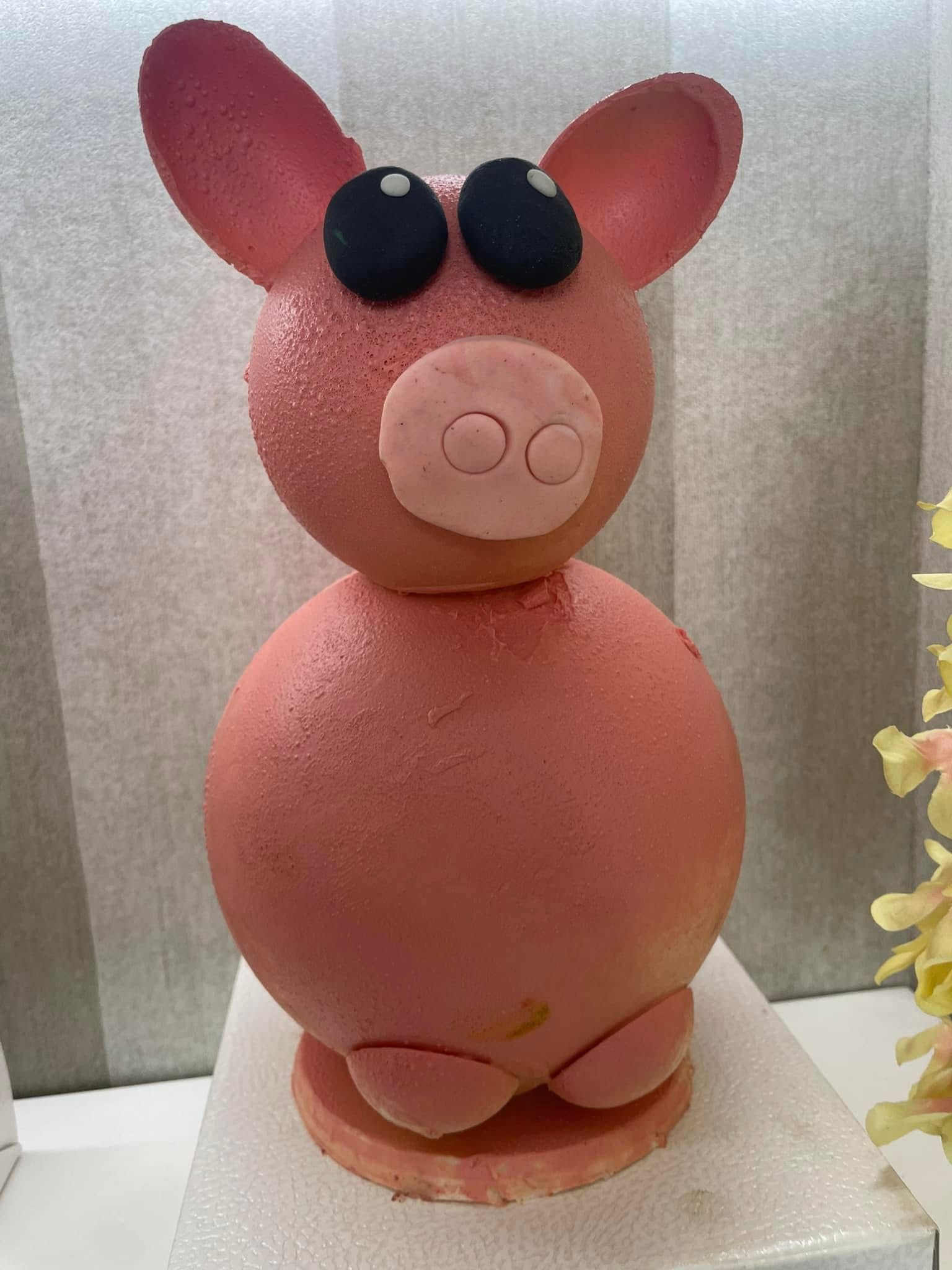 Scultura di maialino rosa con grandi occhi, orecchie e muso.
