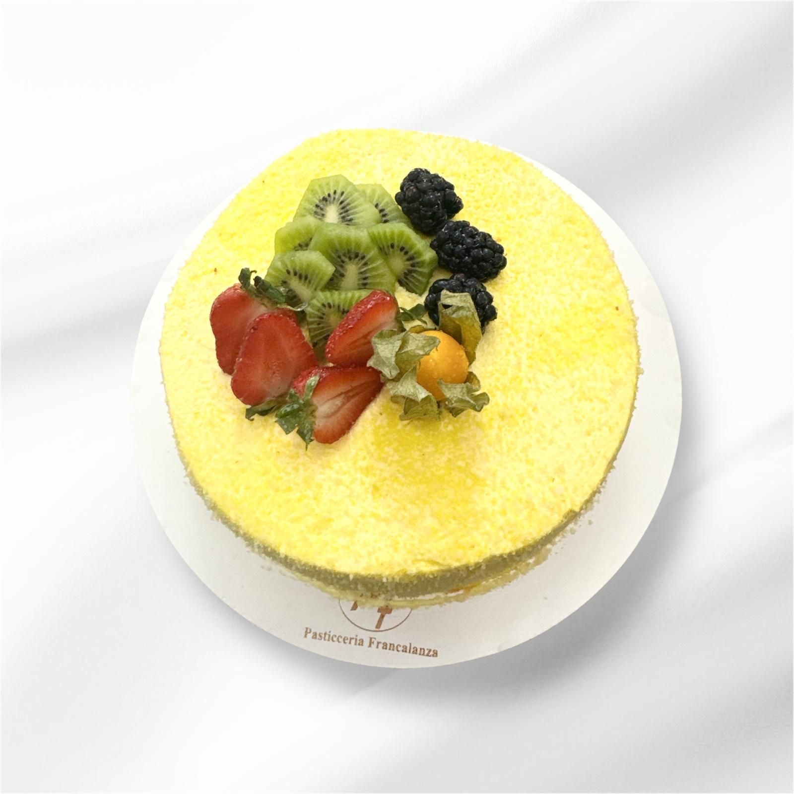 Torta gialla guarnita con kiwi, fragole, more e alchechengi su un piatto bianco.