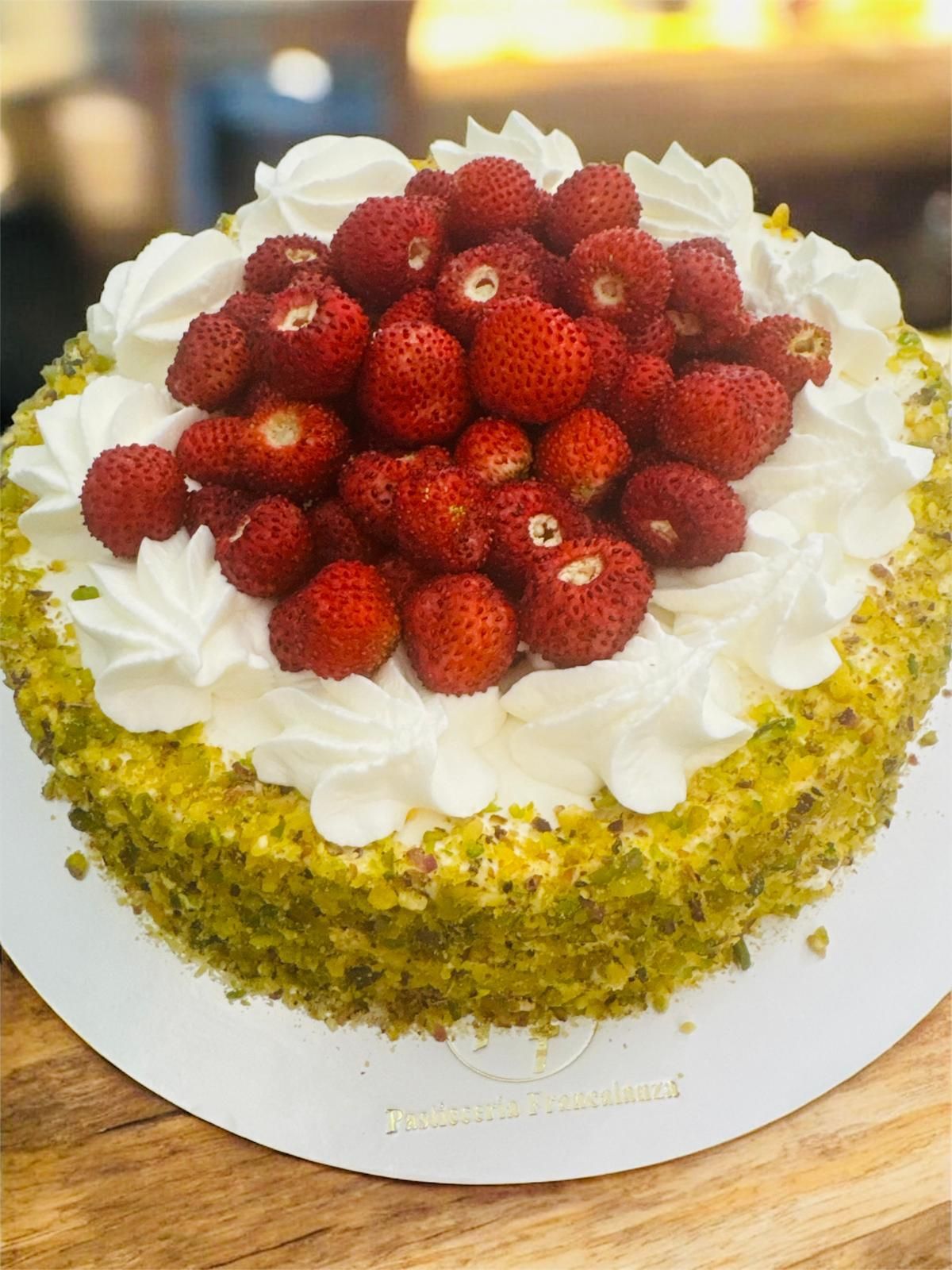 Torta alle fragole con panna montata e crumble di pistacchi.