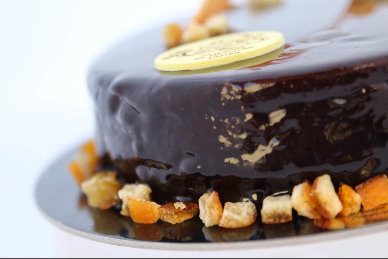 Torta al cioccolato con ganache lucida, decorata con arancia candita e foglia d'oro.