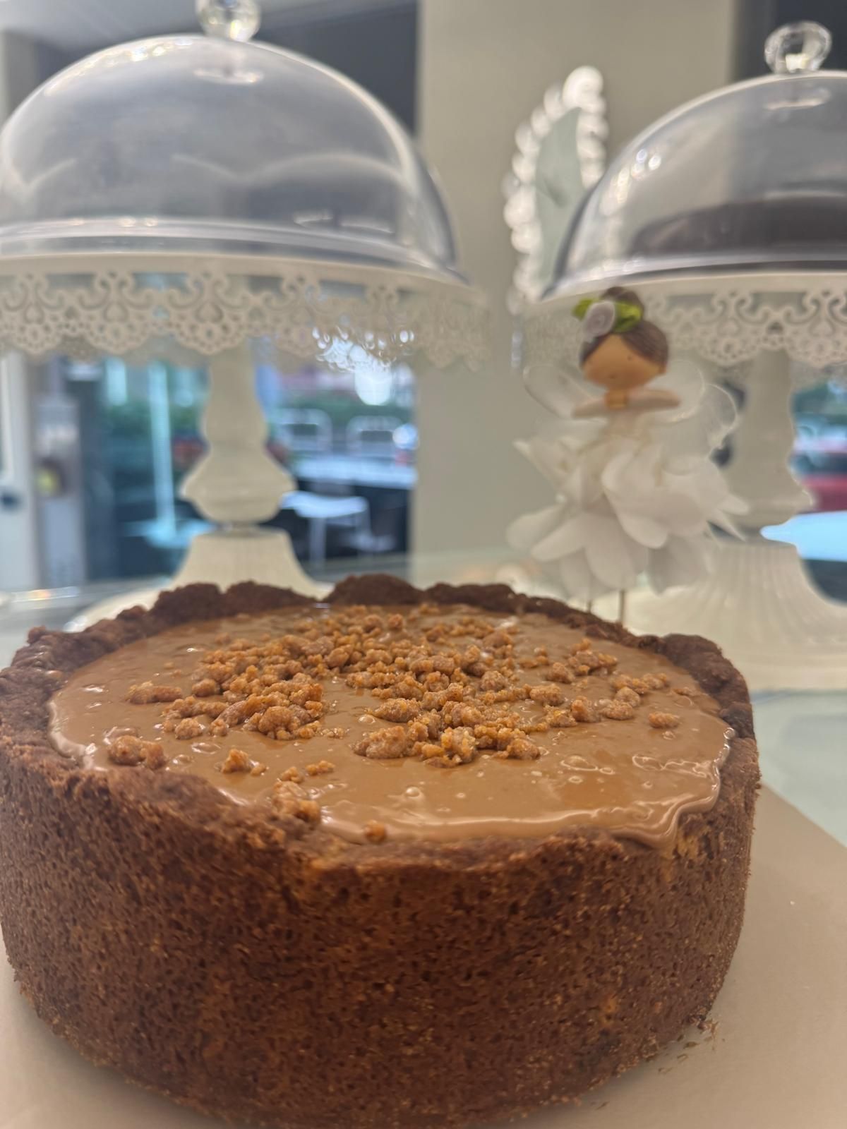 Cheesecake al cioccolato su un piatto bianco, con copertura di briciole e sfondo decorativo.