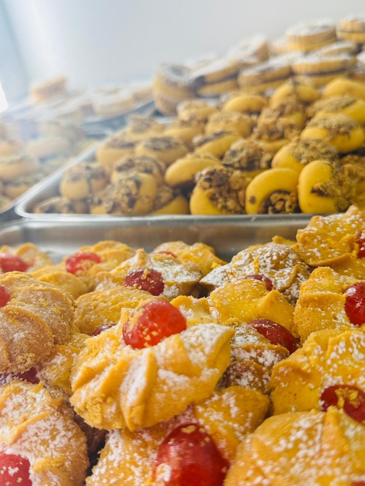Vassoio di biscotti assortiti: con ciliegie in superficie, spolverati di zucchero a velo; altri con noci e ripieni.