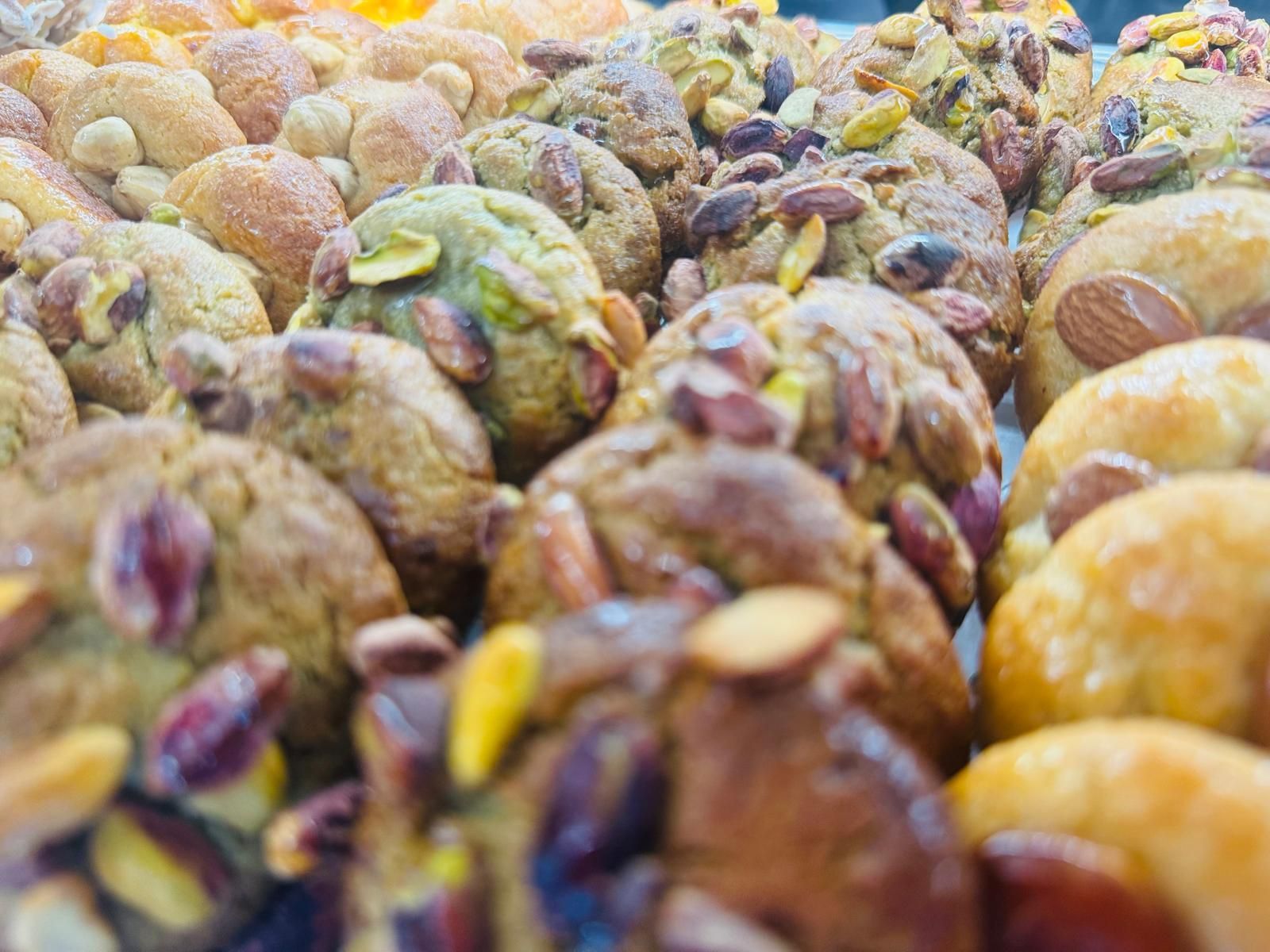 Primo piano di prodotti da forno, probabilmente biscotti, con sopra varie noci, esposti in una panetteria.
