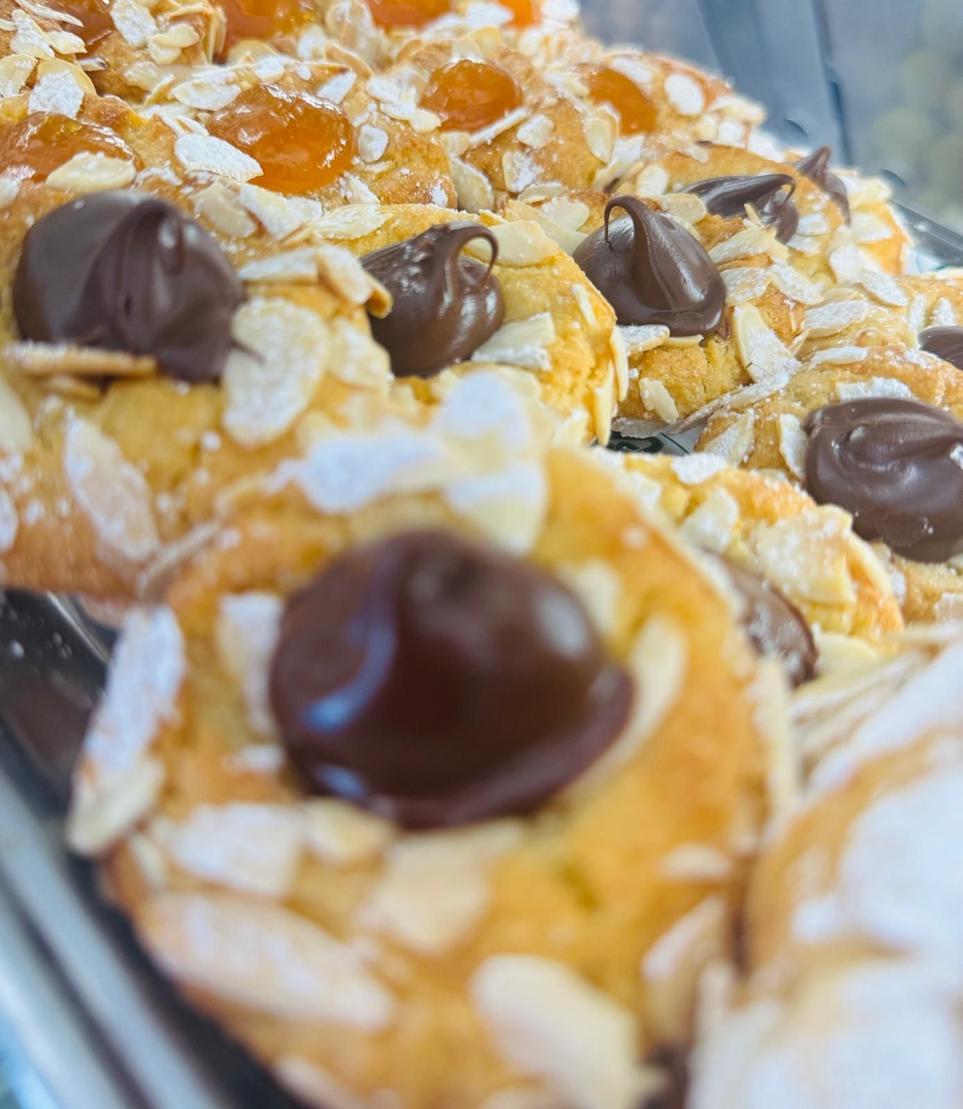 Primo piano di biscotti con scaglie di mandorle, gocce di cioccolato e guarnizione di albicocche.