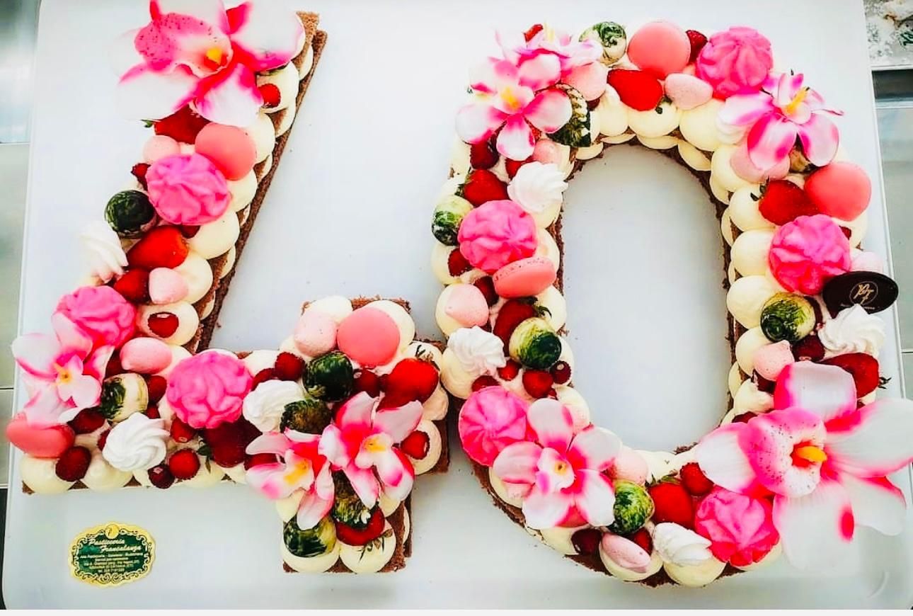 Torta floreale per il 40° compleanno, decorata con fiori rosa, bacche e crema bianca.