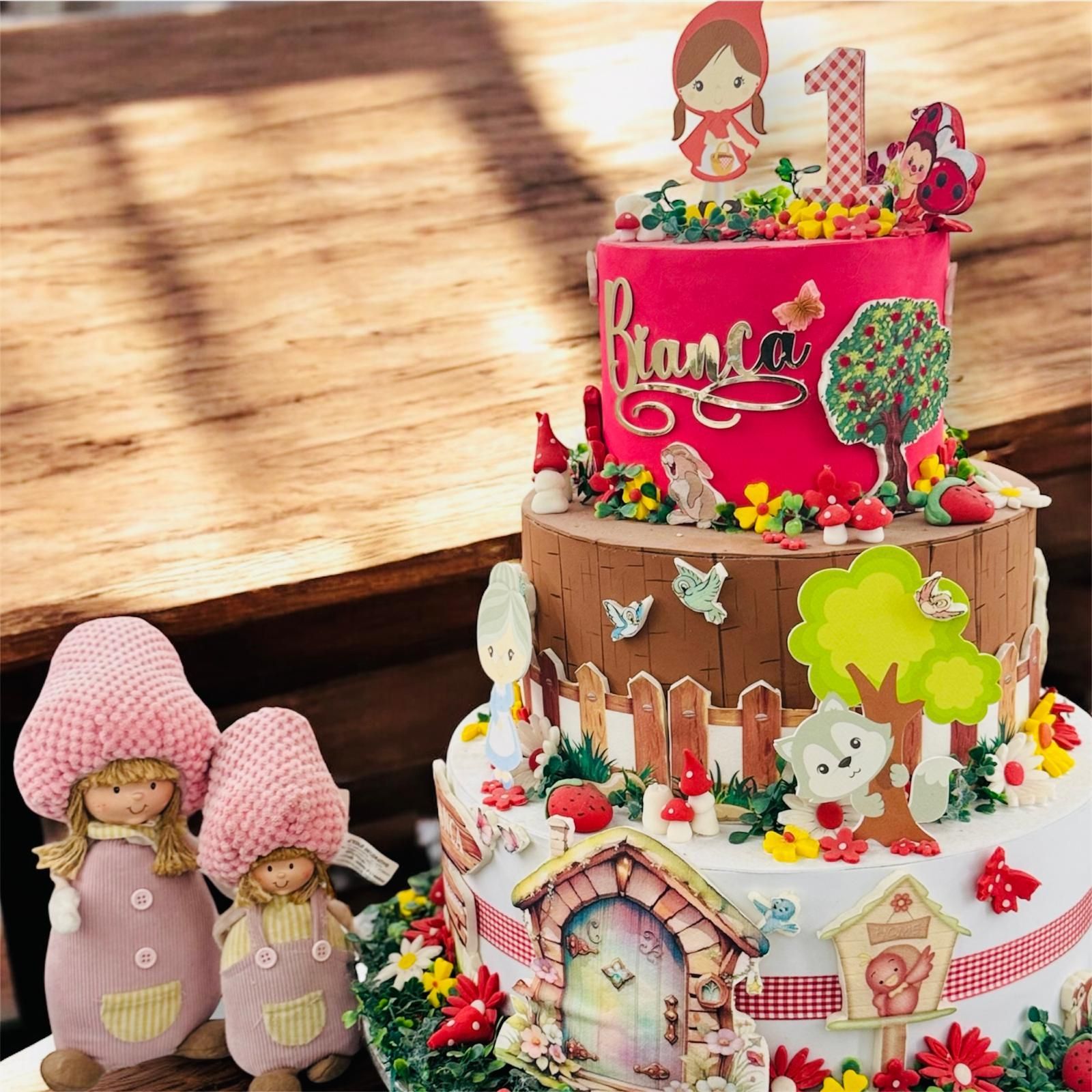 Torta di compleanno a tre piani a tema fiabesco. Decorata con figure, fiori e la scritta
