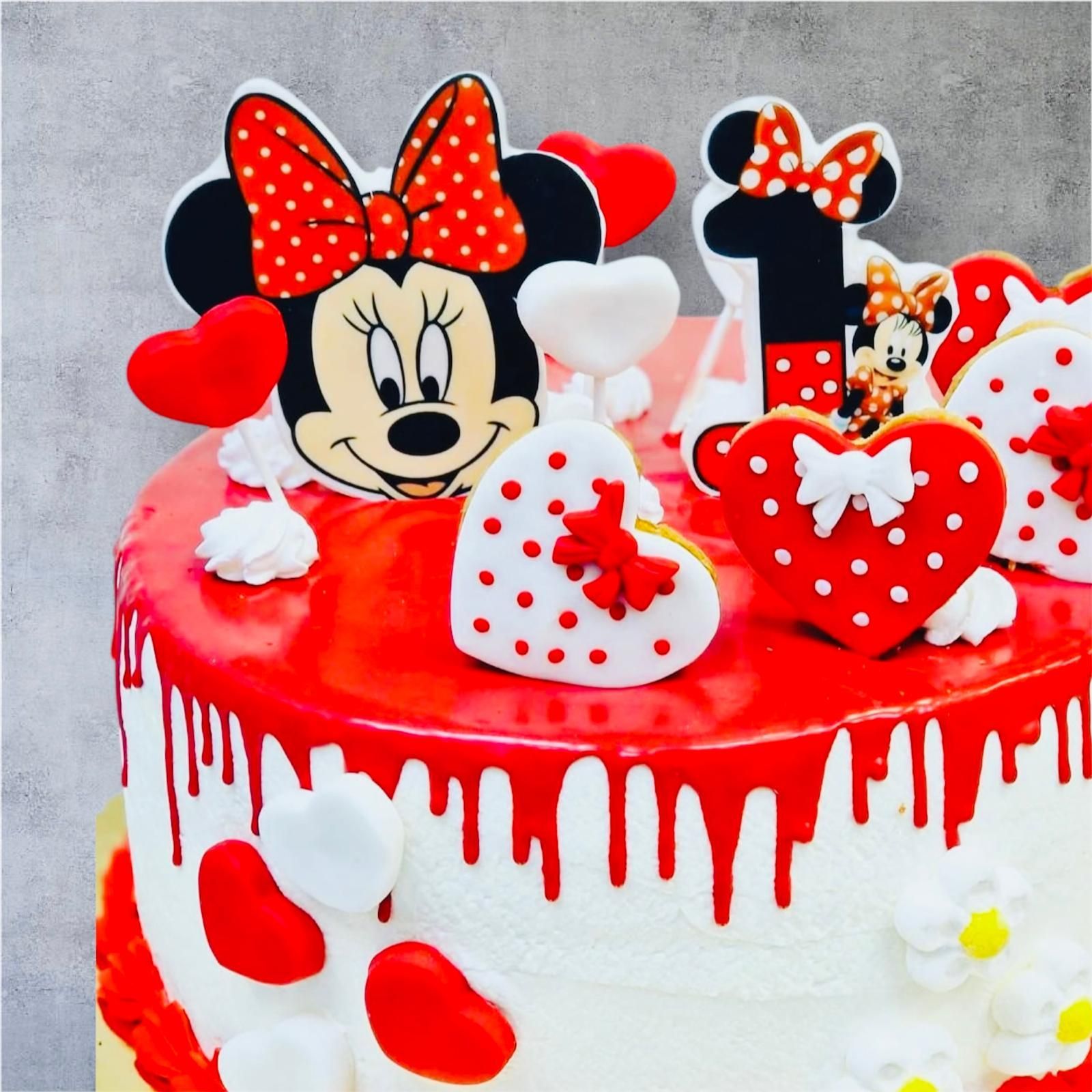 Torta di compleanno a tema Minnie con glassa rossa, decorata con cuori e numero