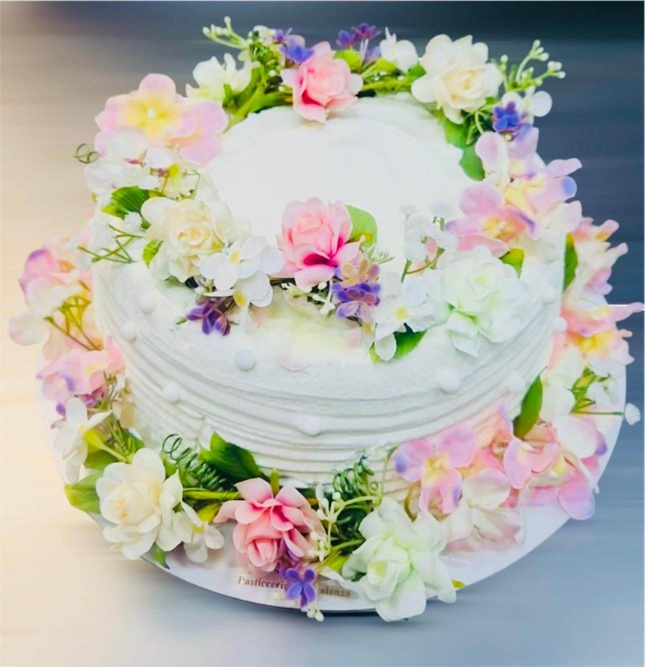 Torta bianca decorata con fiori pastello.