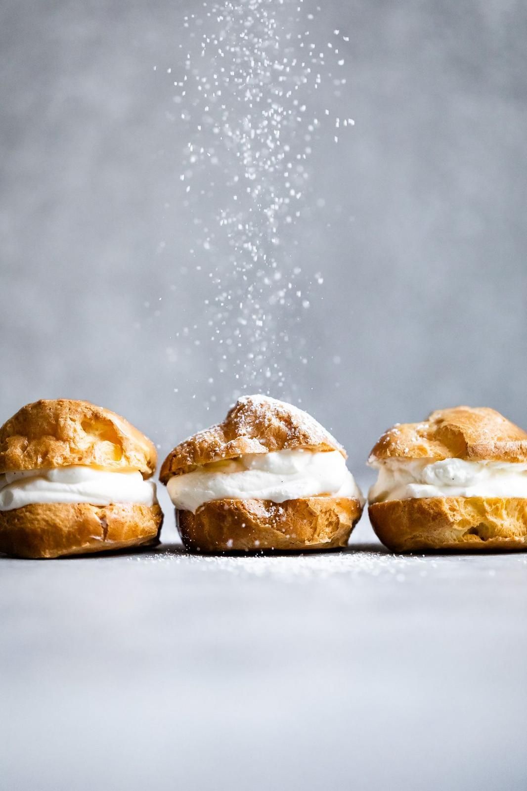 Tre bignè spolverati di zucchero a velo.