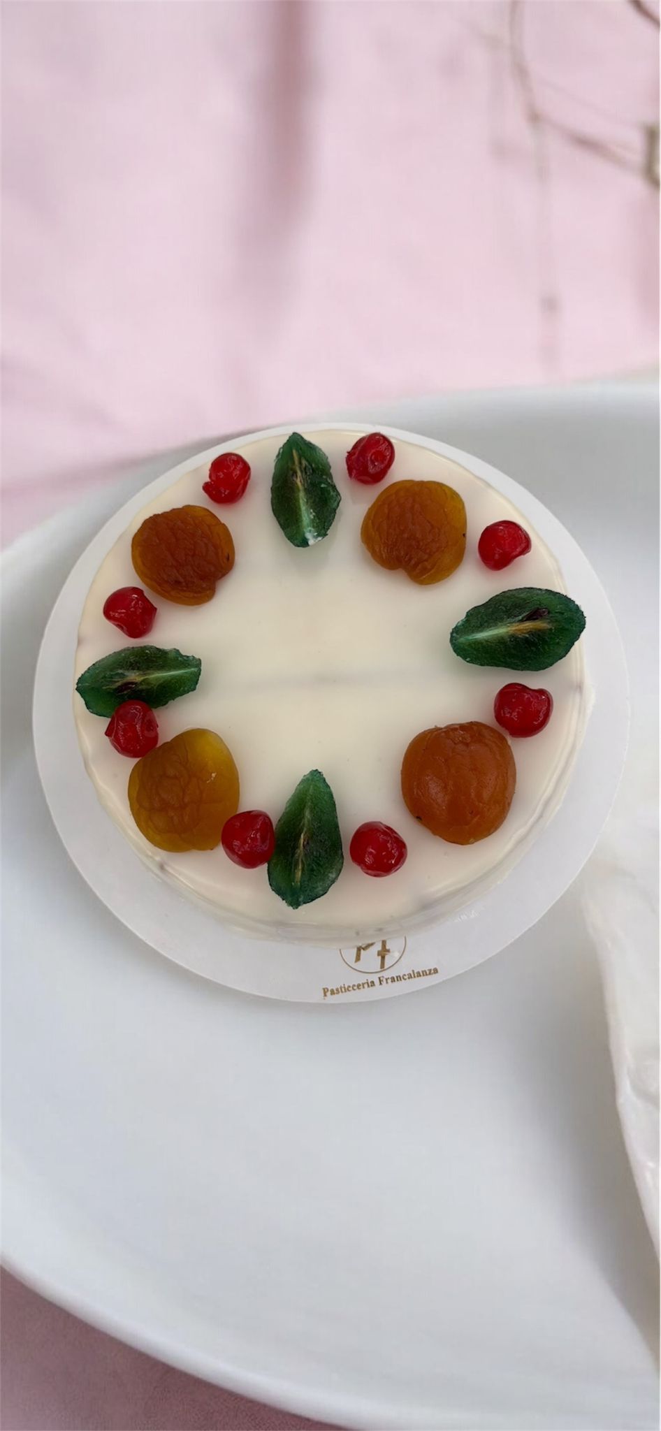 Dolce bianco decorato con frutta su un piatto bianco.