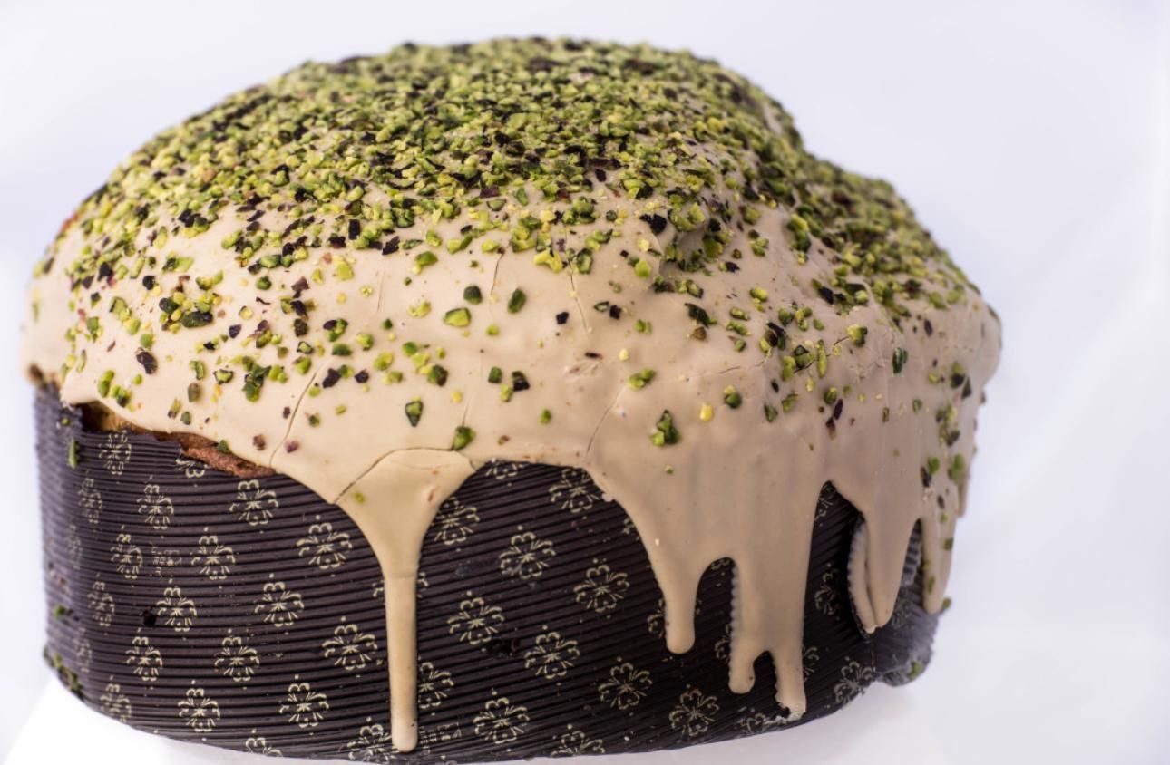 Panettone con glassa a filo e guarnito con pistacchi tritati.