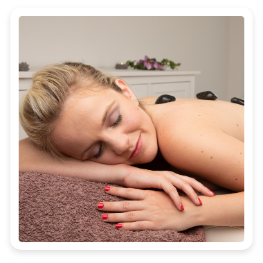 Eine Frau liegt auf dem Bauch und bekommt eine Hot Stone Massage