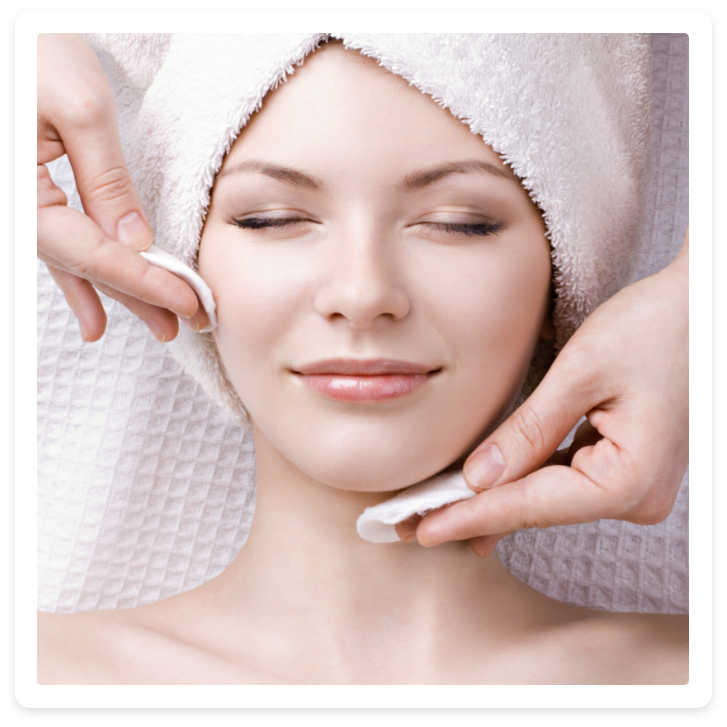 Eine Frau mit einem Handtuch um den Kopf gewickelt bekommt eine Gesichtsbehandlung