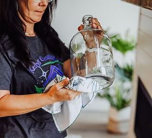 A woman is cleaning a glass jar with a cloth.