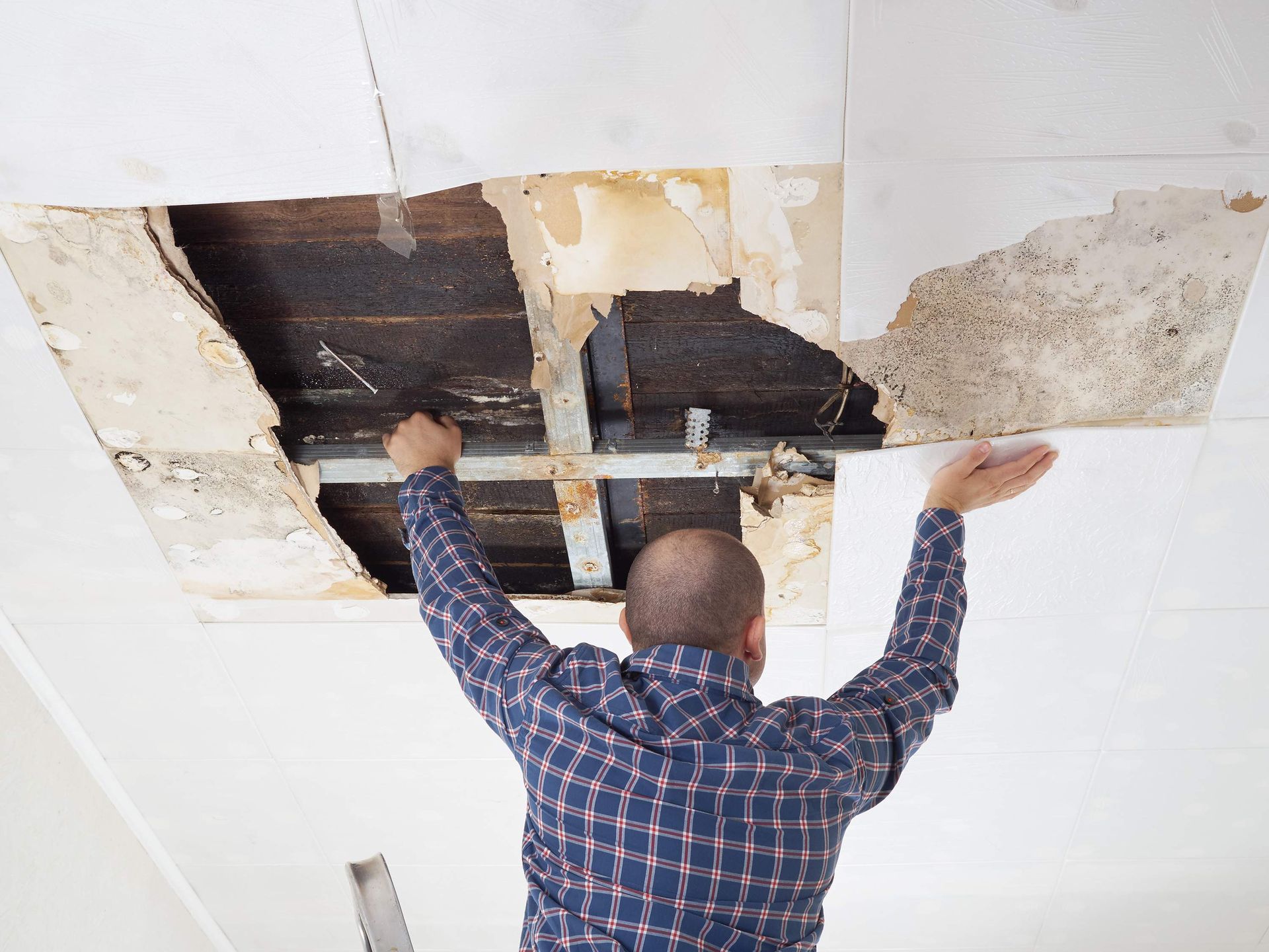 A man is looking through a hole in the ceiling