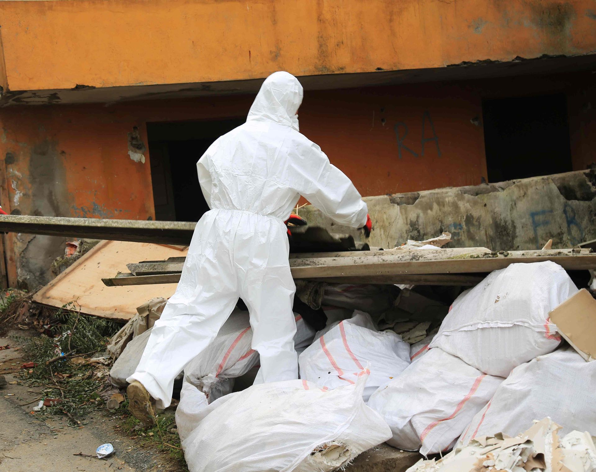 A man in a protective suit is working on a pile of trash