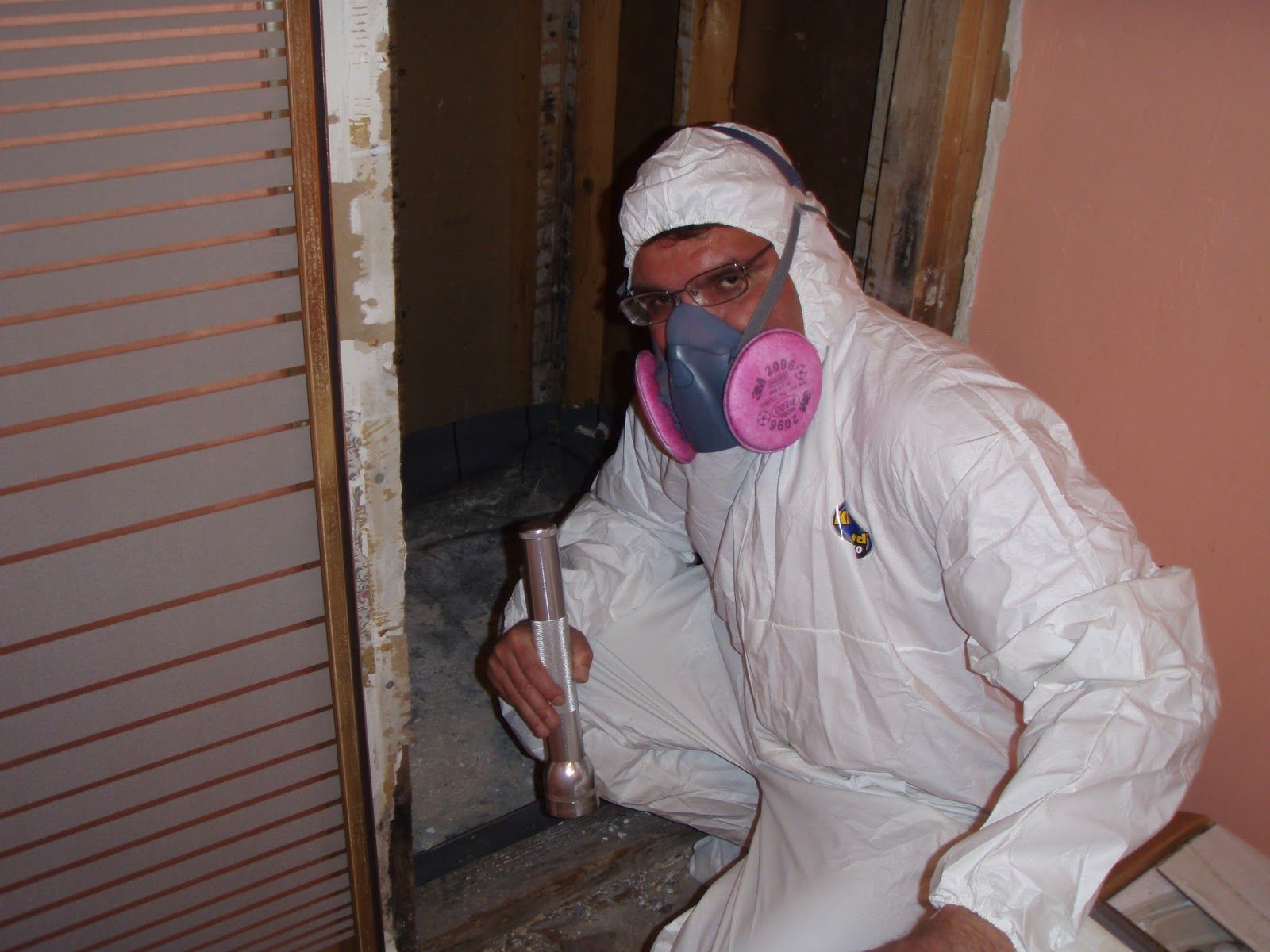 A man wearing a white coverall and a pink gas mask