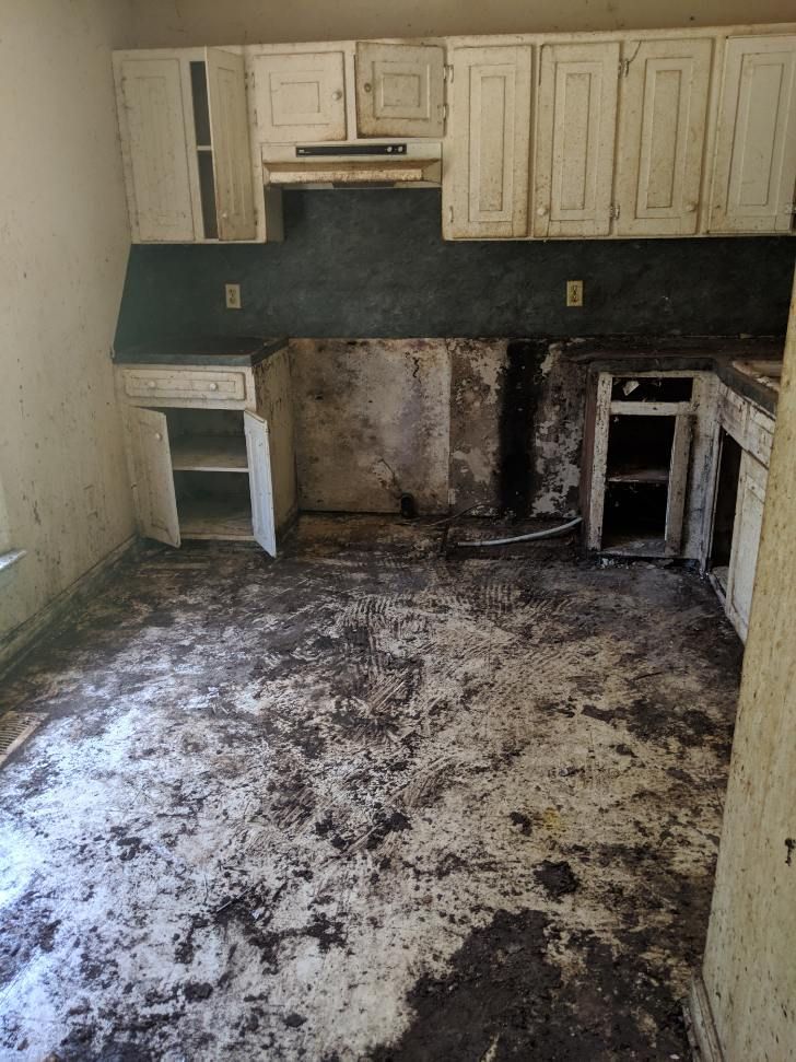a kitchen with a lot of dirt on the floor and cabinets