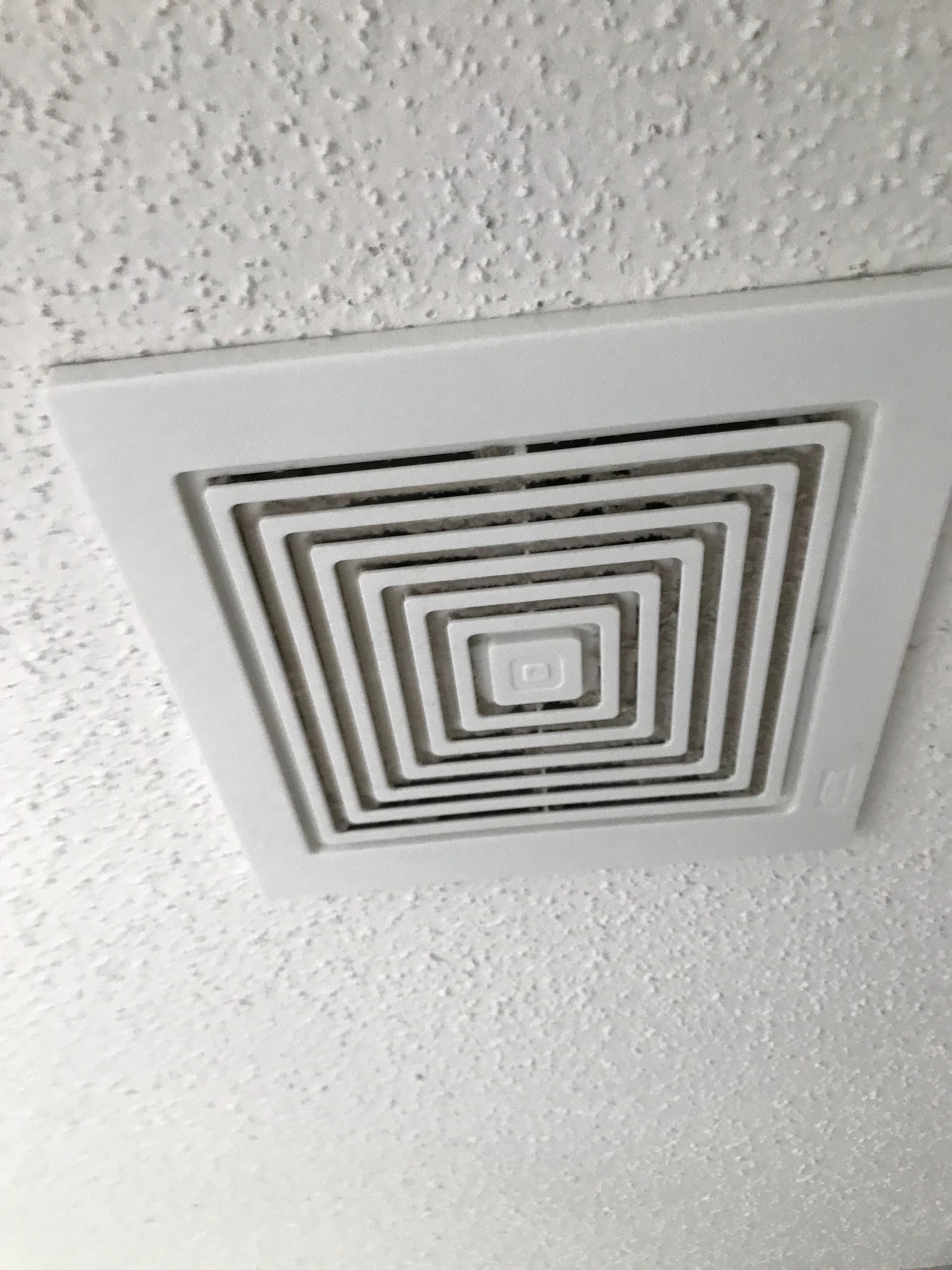 a square air vent is hanging from the ceiling of a room