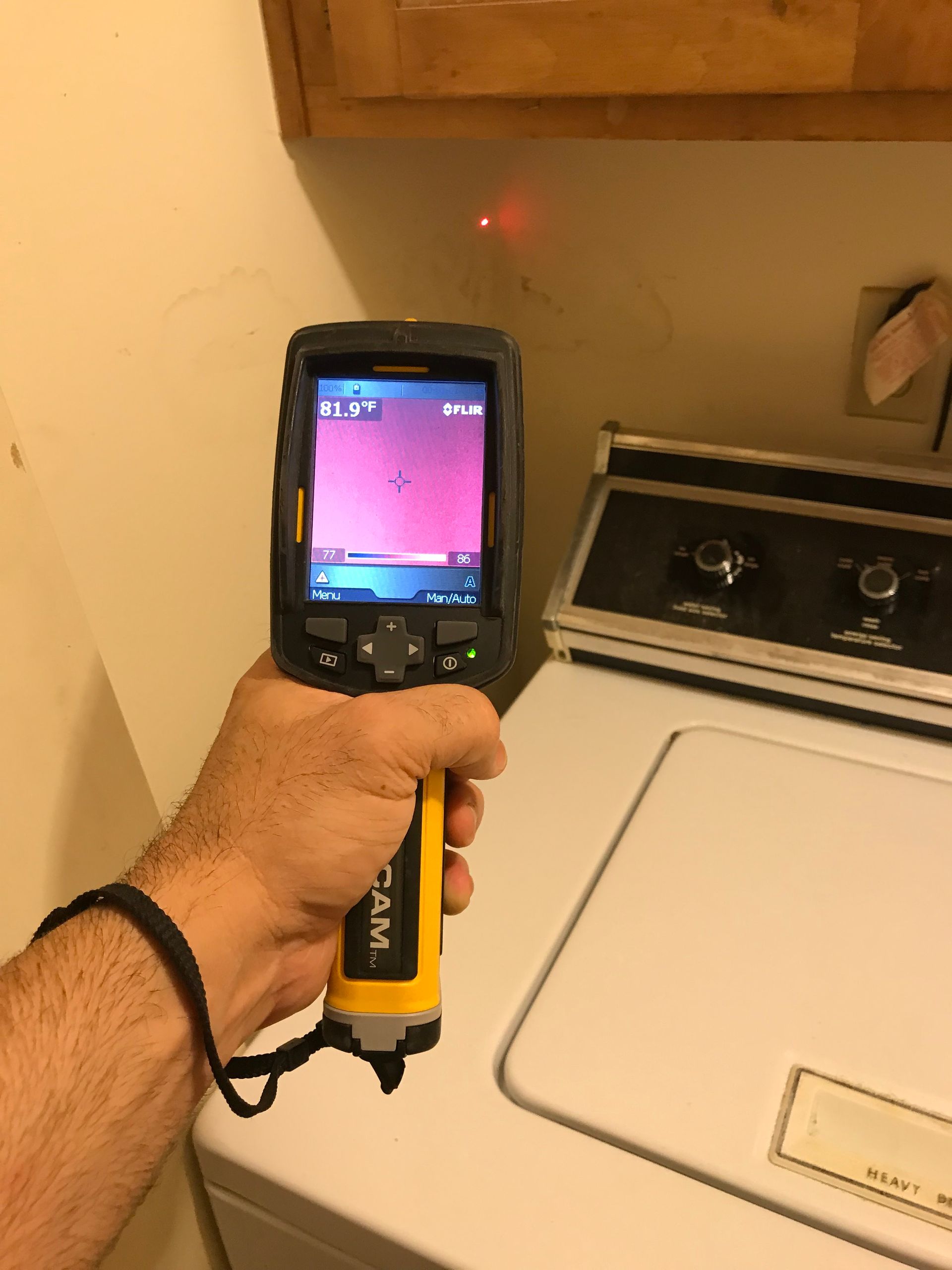 a person is holding a thermal camera in front of a washer and dryer