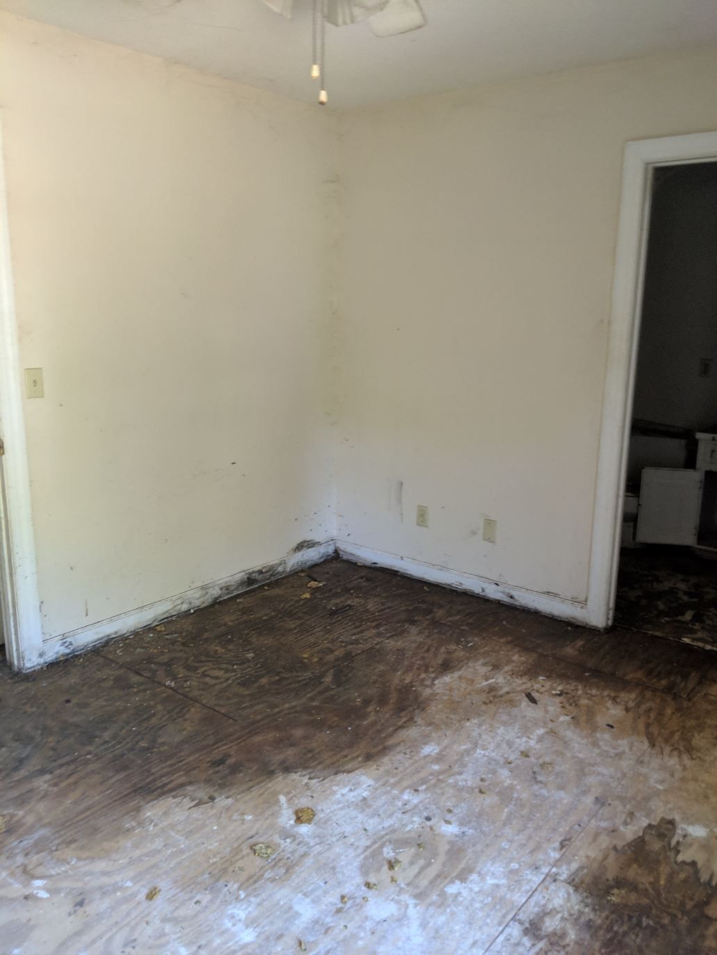 an empty room with a muddy floor and white walls