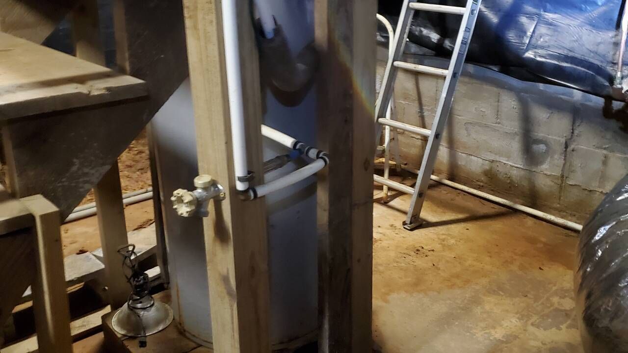 A ladder is sitting next to a pipe in a basement.