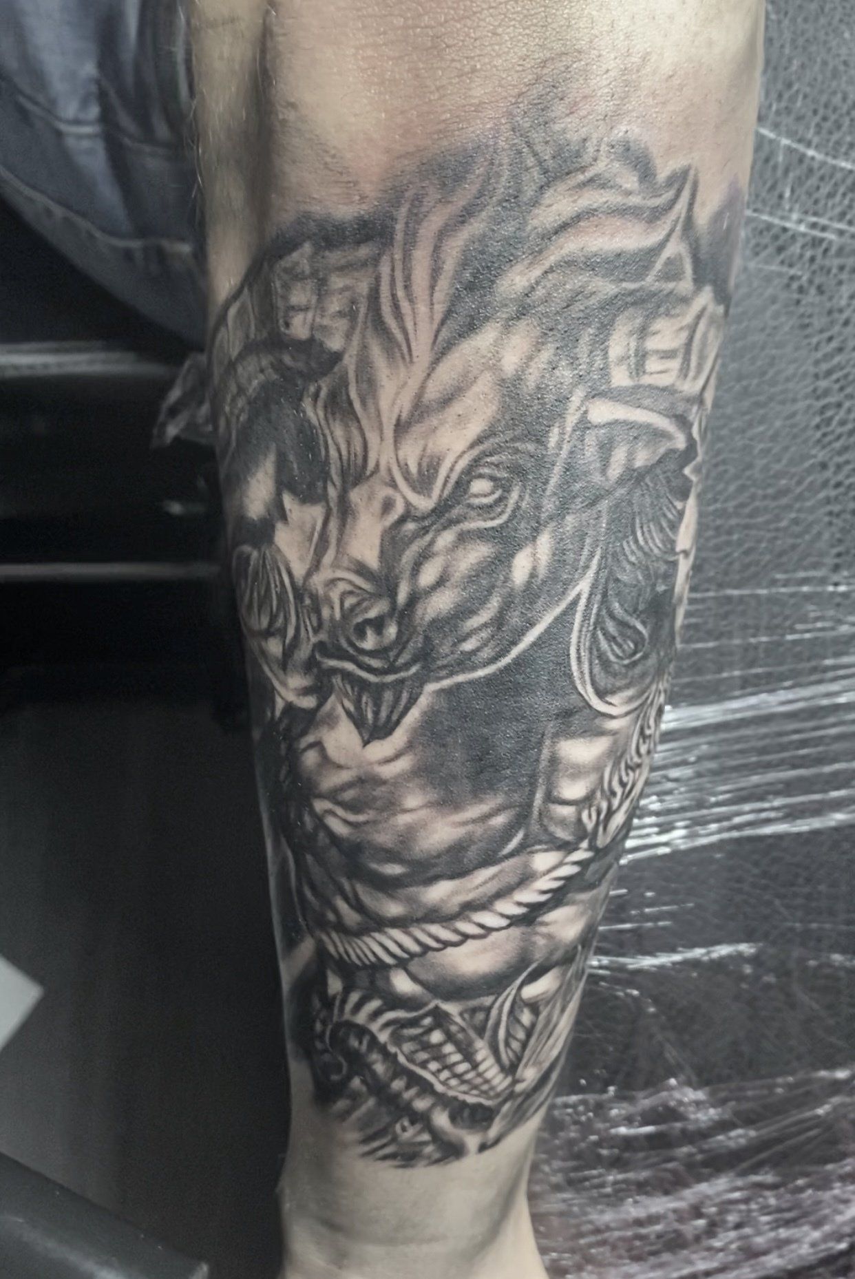 A black and white tattoo of a horse on a person 's leg.