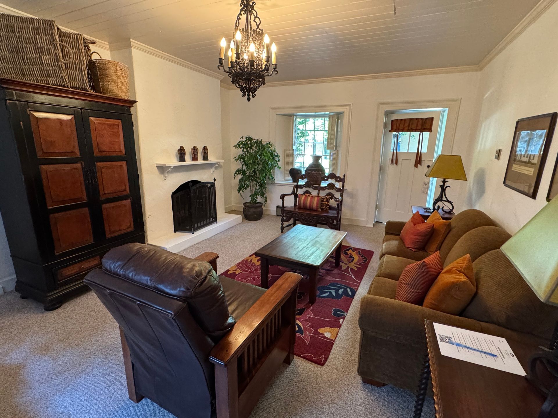 Living room with fireplace, sofa, armchair, coffee table, and tall cabinet.
