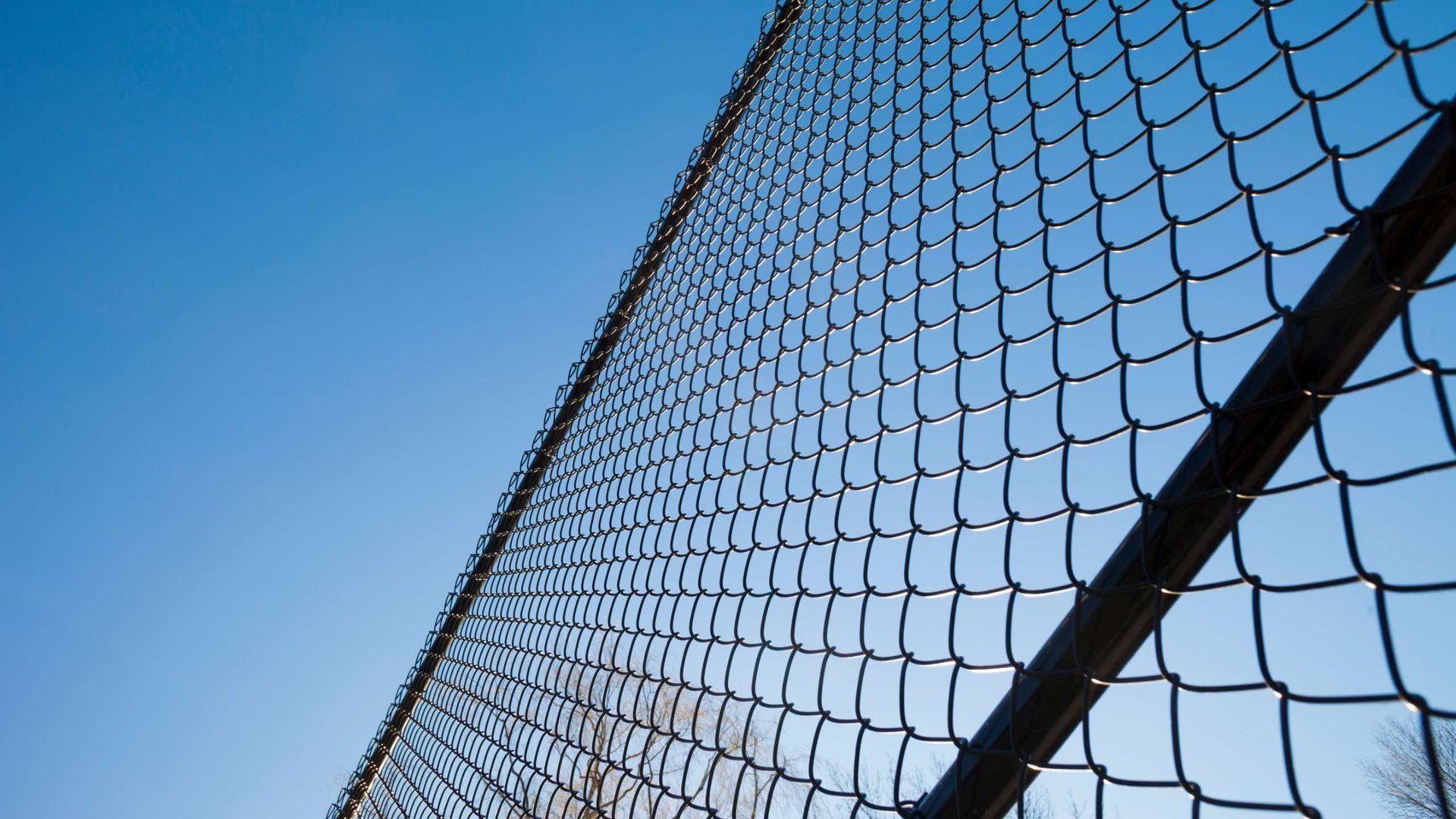 Looking up at a chain link fence against a blue sky.