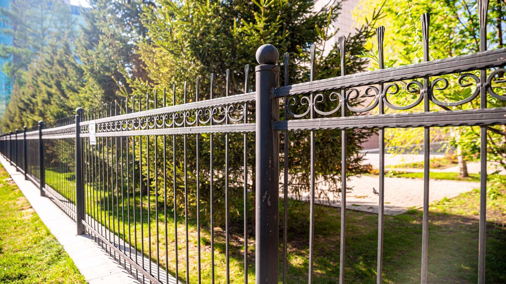 A wrought iron fence surrounds a lush green field.
