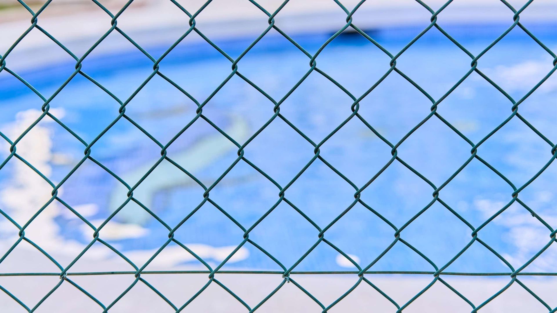 A chain link fence surrounds a swimming pool.