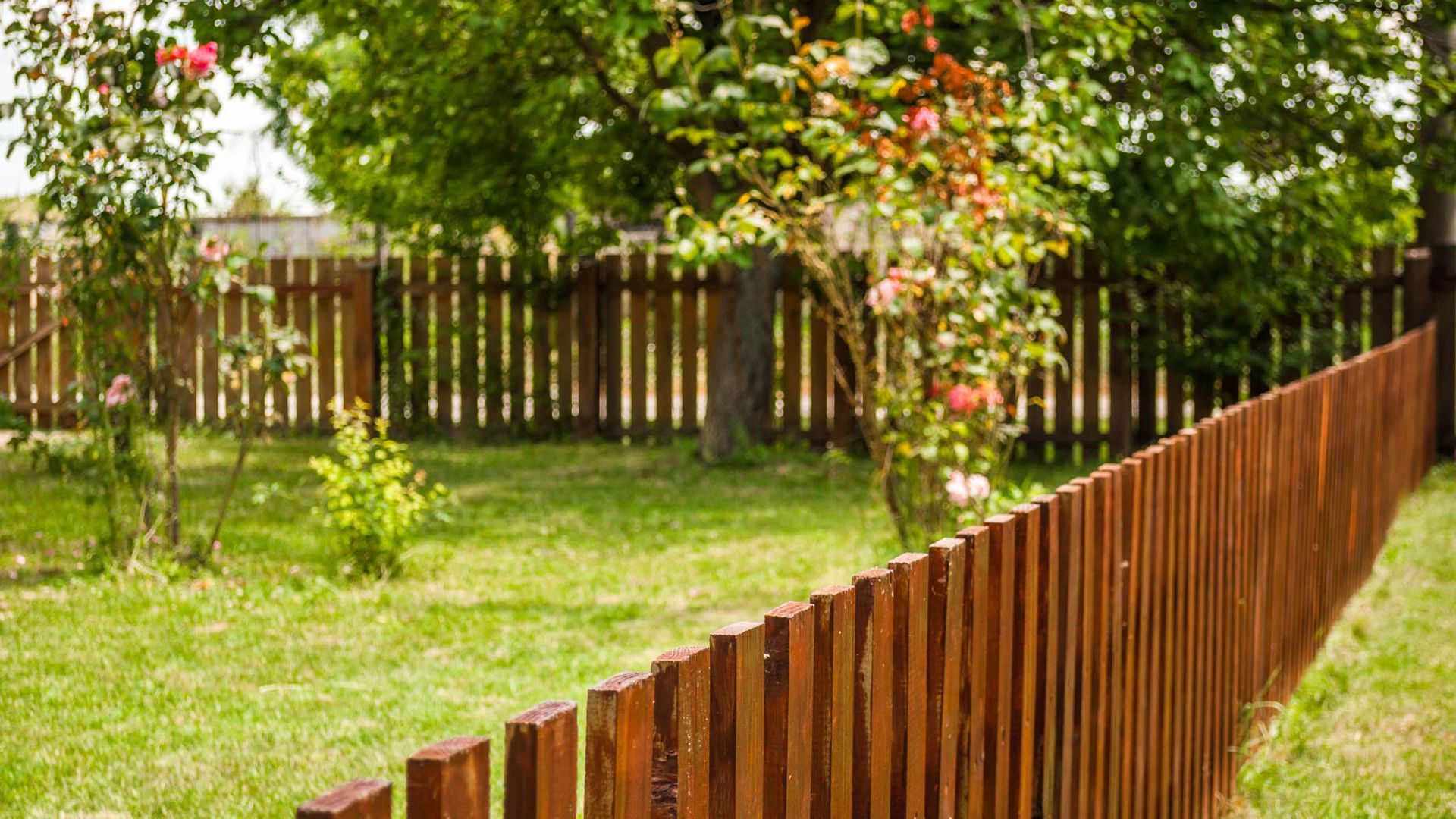 A wooden fence surrounds a lush green yard.