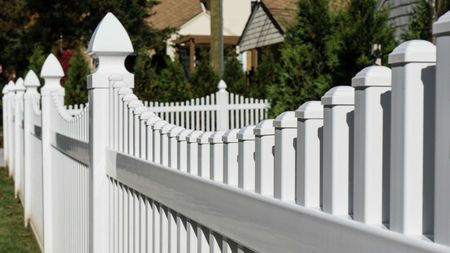 A white picket fence with a house in the background